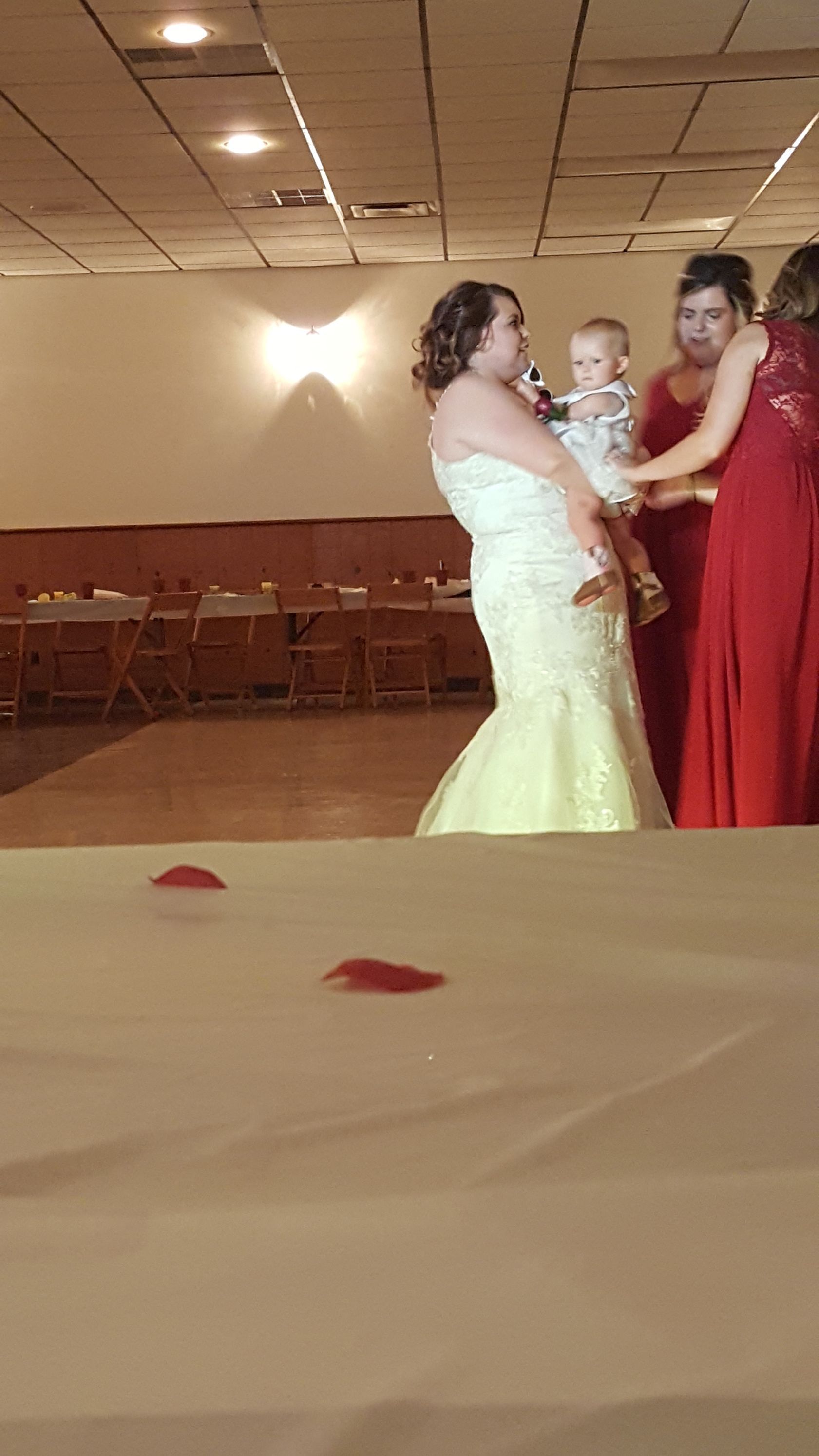 Three people dancing in a banquet hall, with a woman in a light yellow gown and another in a red dress.