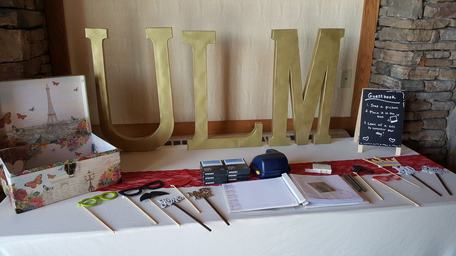 Table display with gold “ULM” letters, papers, pens, and a chalkboard sign on a white tablecloth