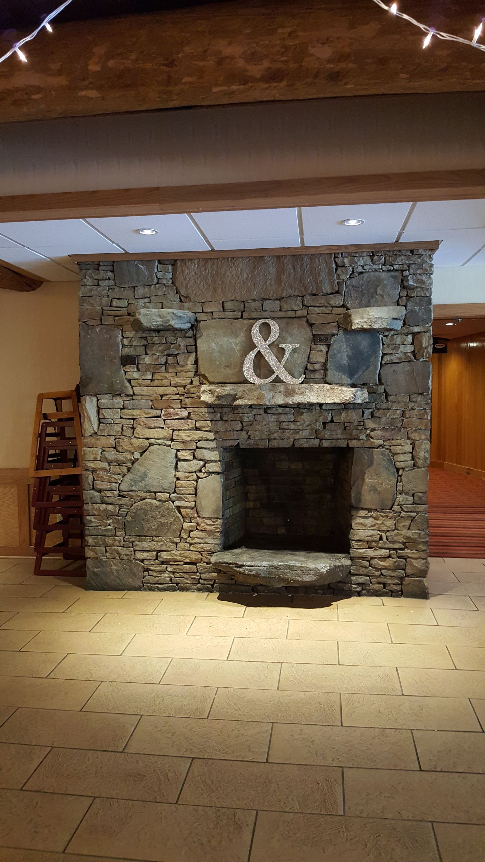 Stone fireplace wall with a large decorative ampersand in a rustic indoor room