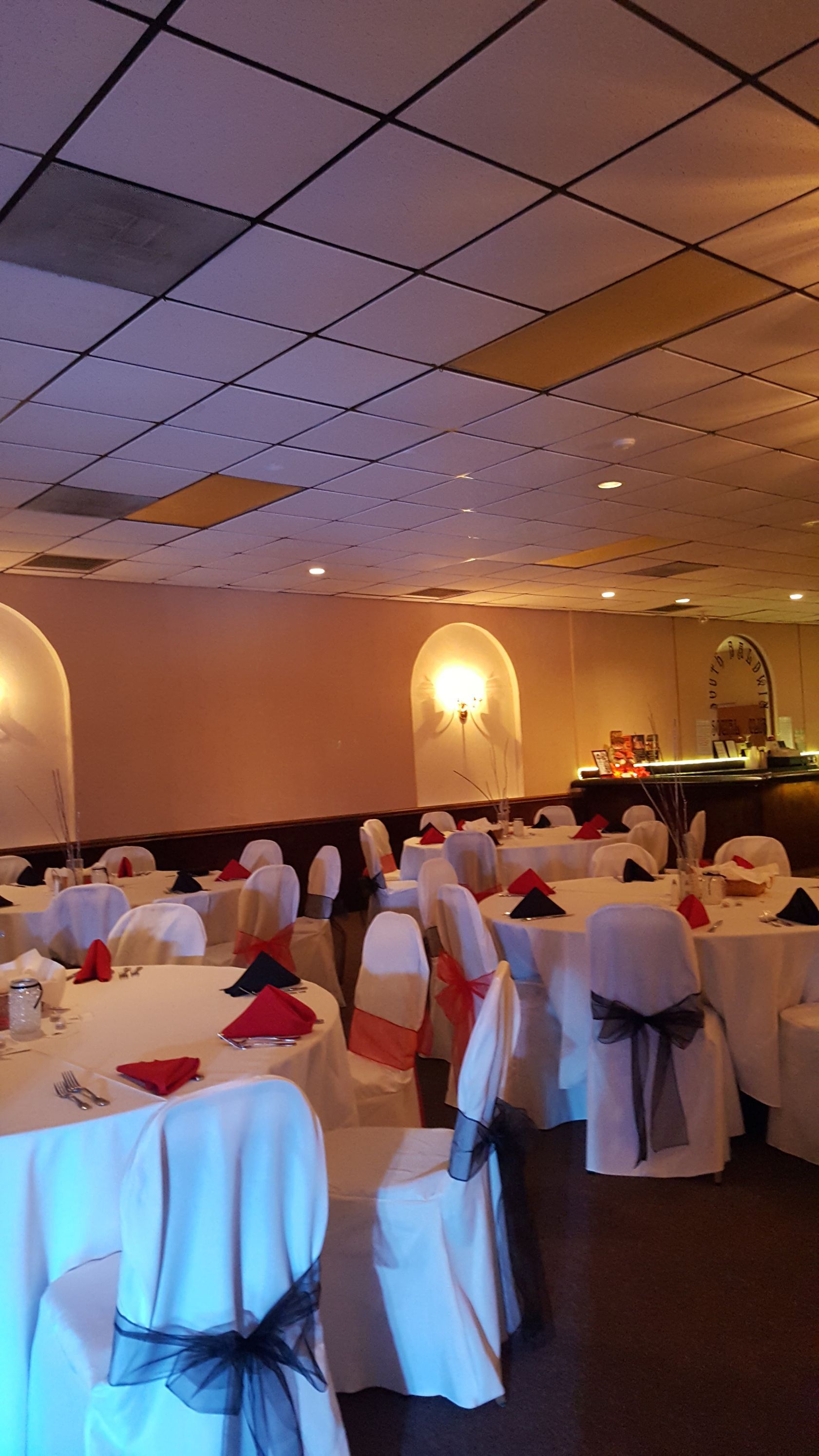 Elegant banquet hall with white-covered chairs, round tables, and warm wall lighting prepared for an event