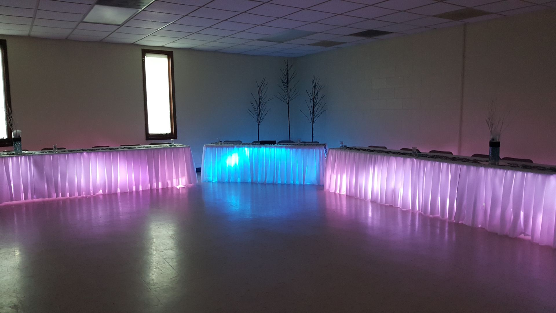 Curved reception desk with pink and blue LED lighting in a dim room