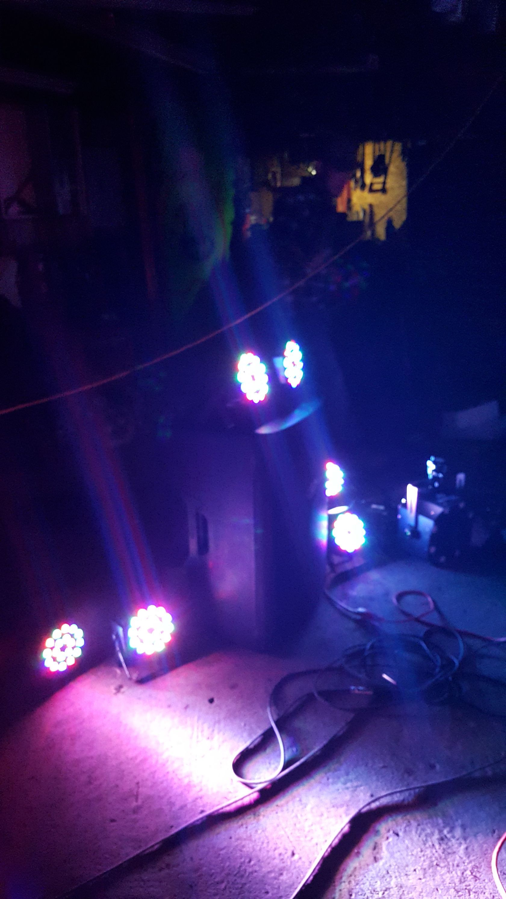 Purple stage lights on a dark floor, with cables and equipment in a dim venue
