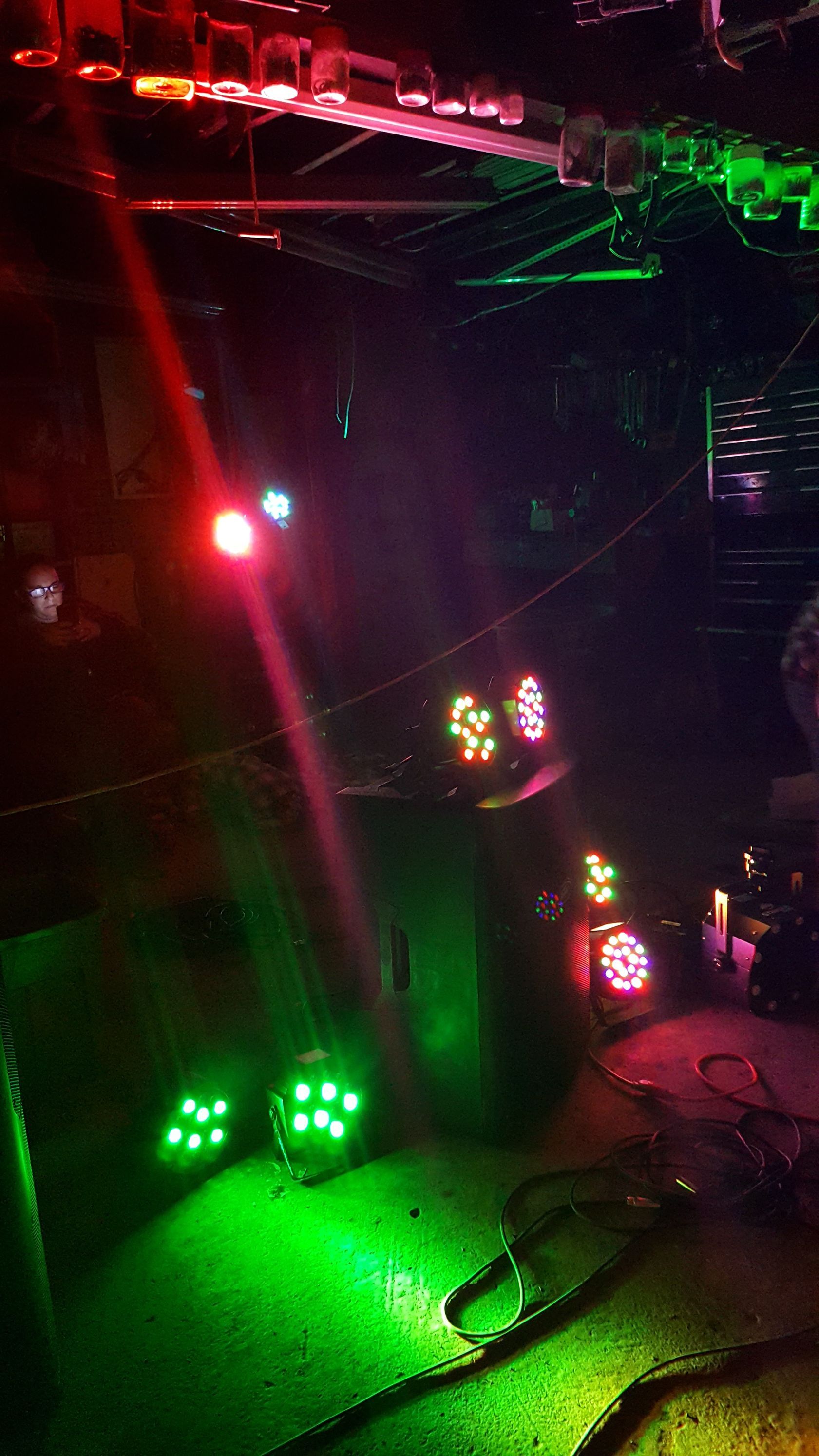Dim stage with red and green laser lights and spotlights shining on a dark floor