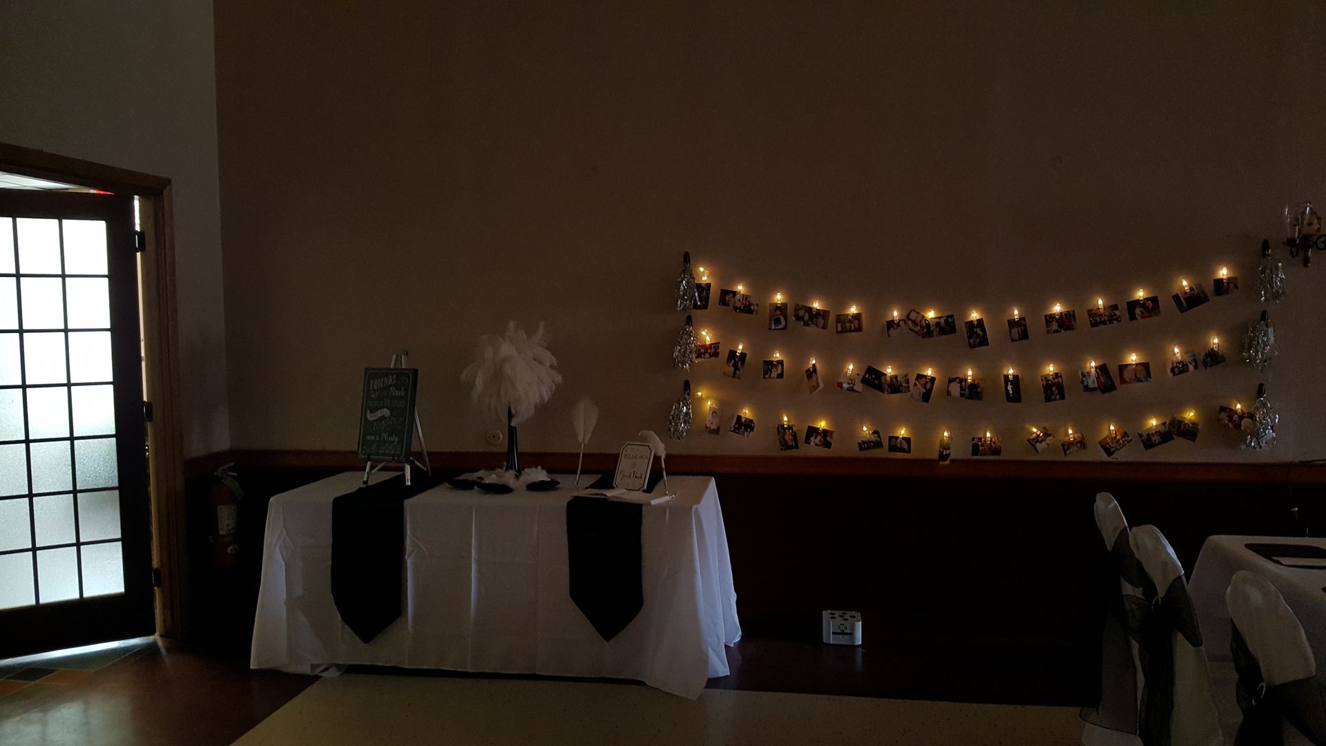 Dimly lit room with a white-draped table and a candle-lit decorative wall display.