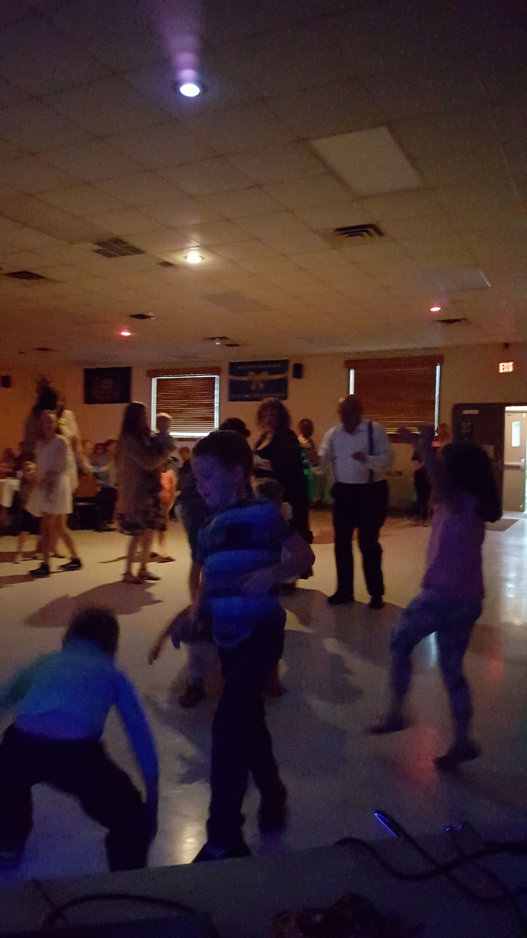 People dancing in a dimly lit room with a projector beam shining from the ceiling.