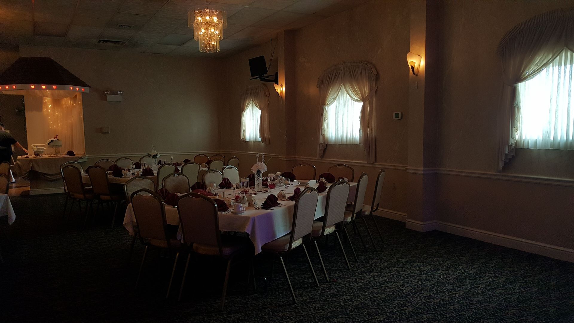 Banquet hall with round tables set with white tablecloths and chairs under warm chandeliers