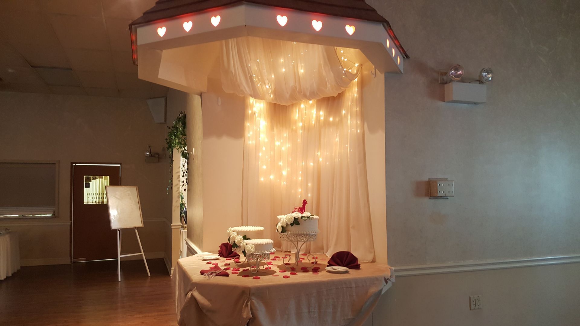 Decorated dessert table with pink lights and draped fabric in a softly lit indoor room