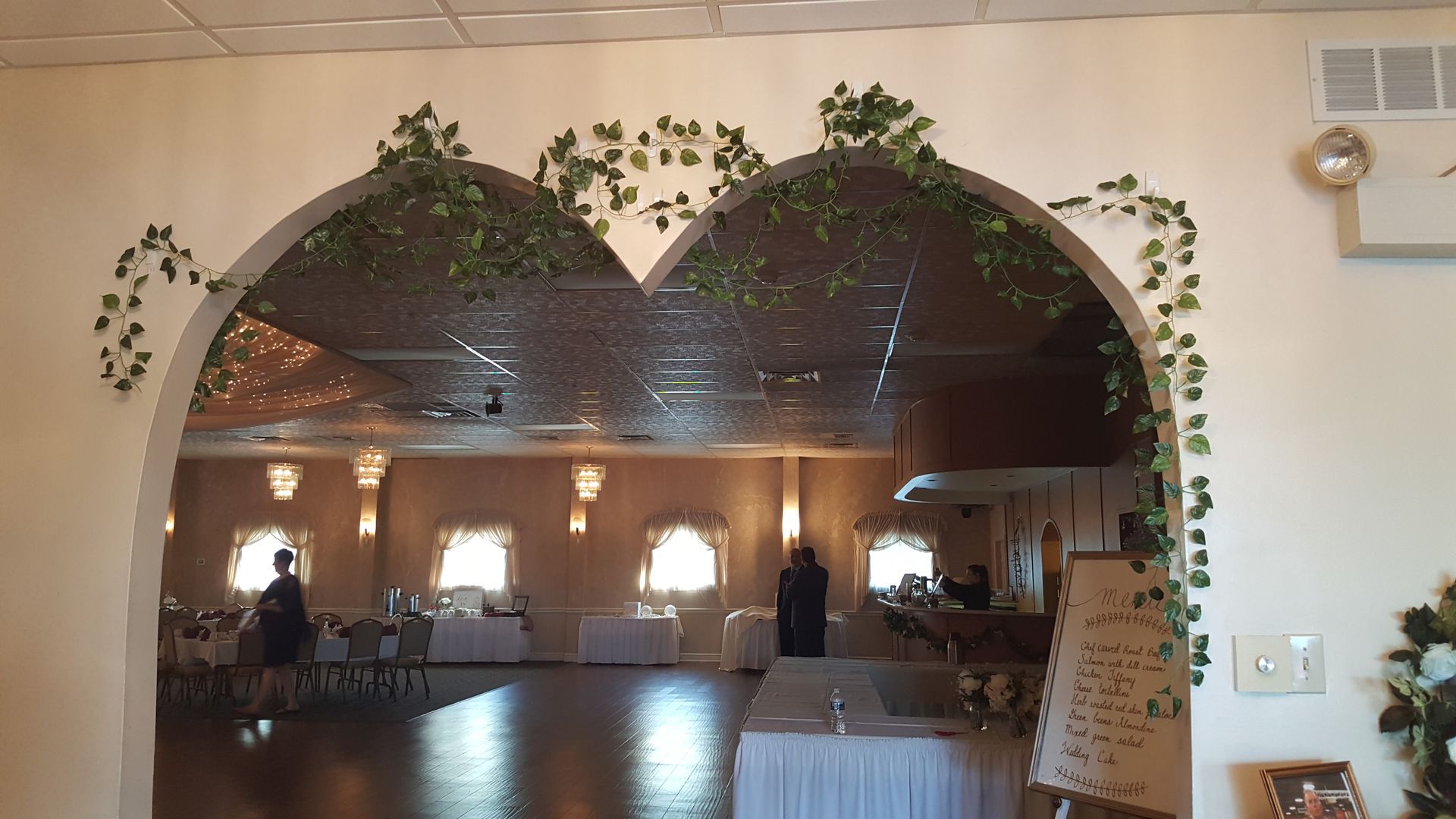 Arched restaurant dining room with warm lighting, hanging vines, and tables set for guests.