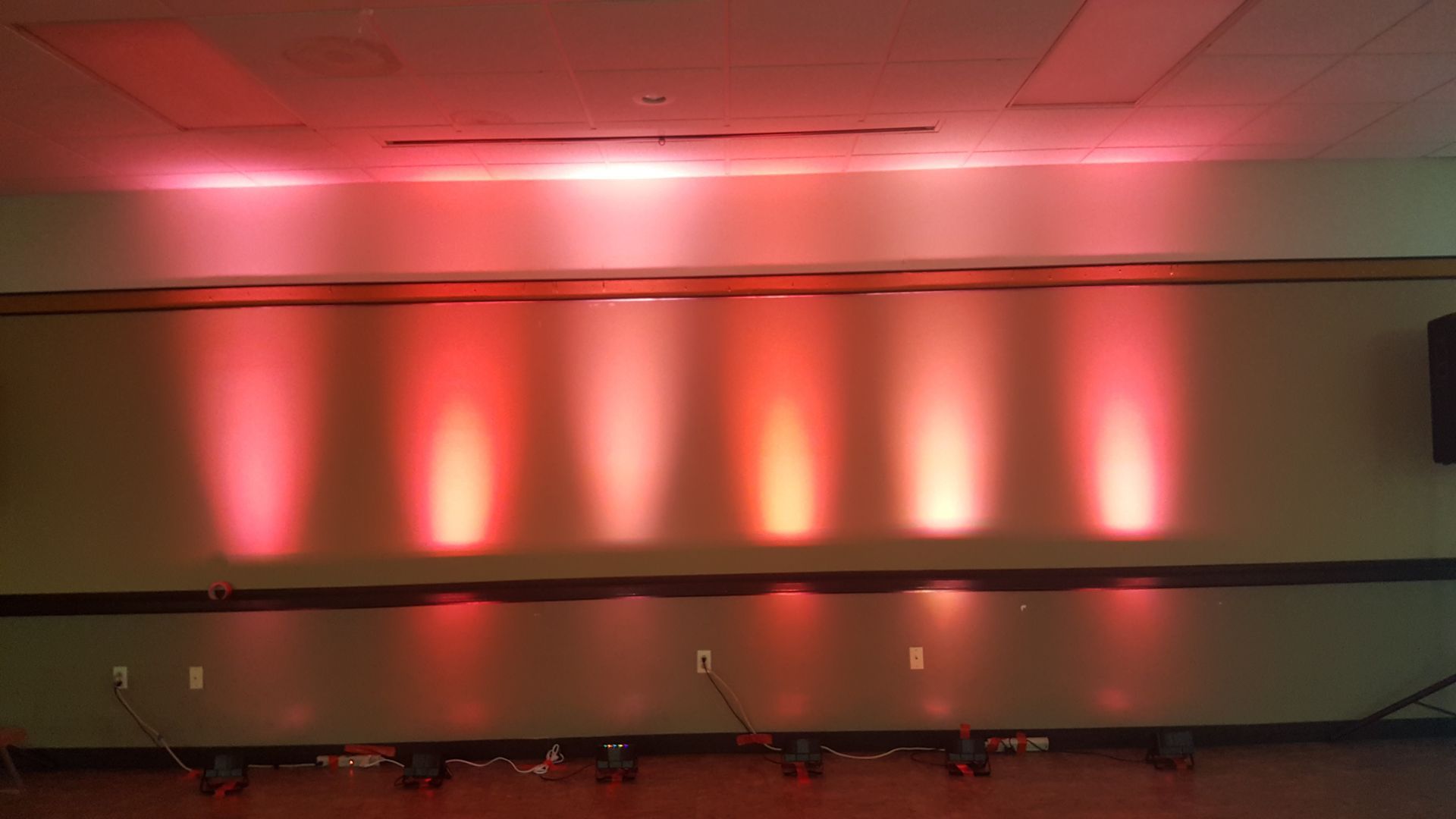 Wall with red uplighting and glowing vertical light columns in a dim room