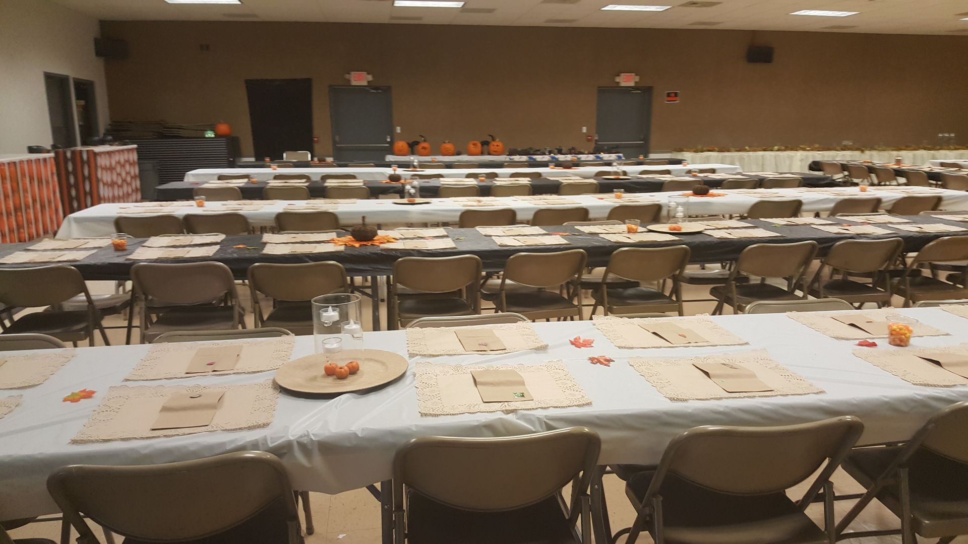 Empty conference room with rows of tables and chairs set for a meal or event.