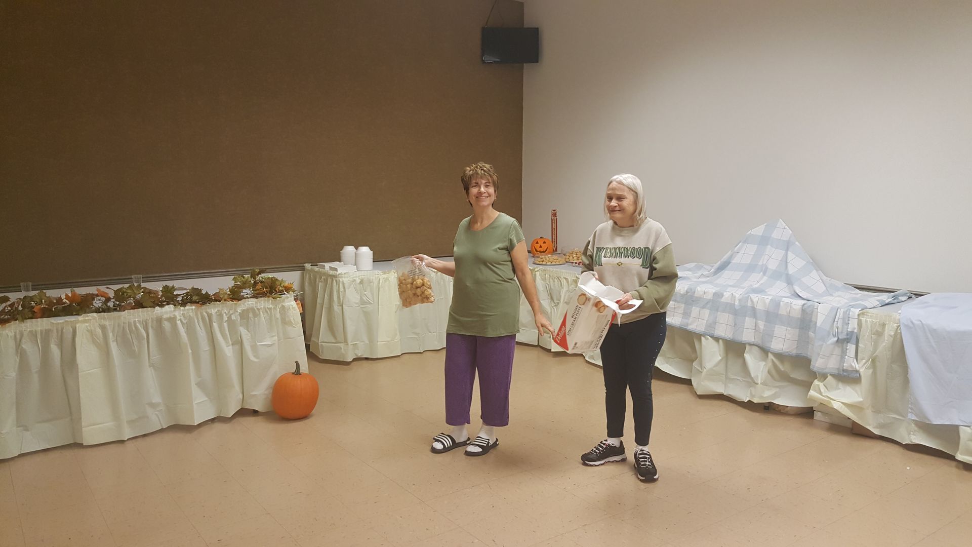 Two people standing in a decorated room with tables, draped fabrics, and an orange ball on the floor