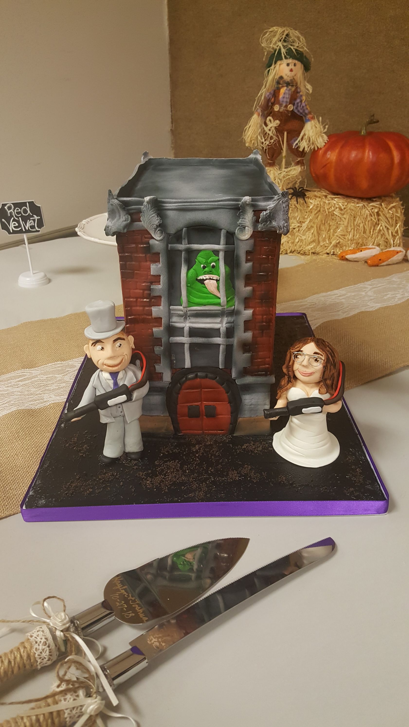 Halloween miniature scene with a small haunted house, two figurines, and a pumpkin on a tabletop