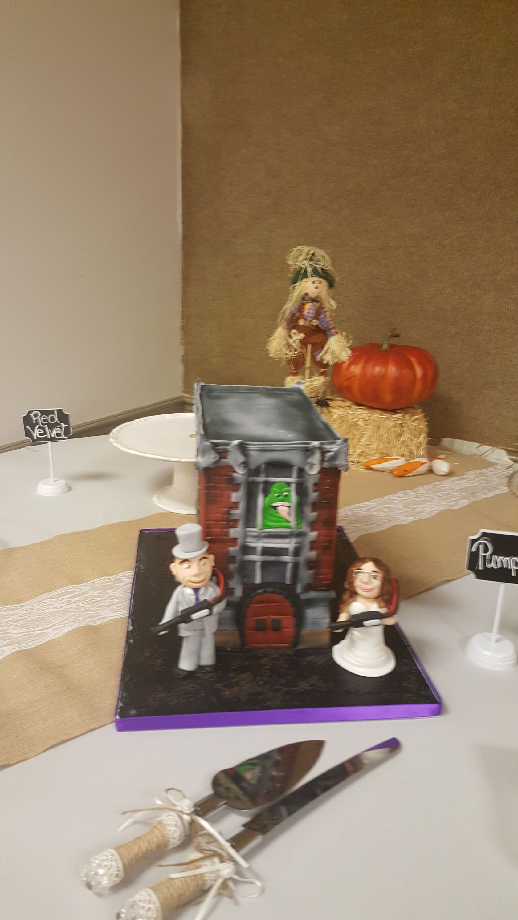 Halloween tabletop scene with a small haunted house, pumpkins, and figurines on a white table