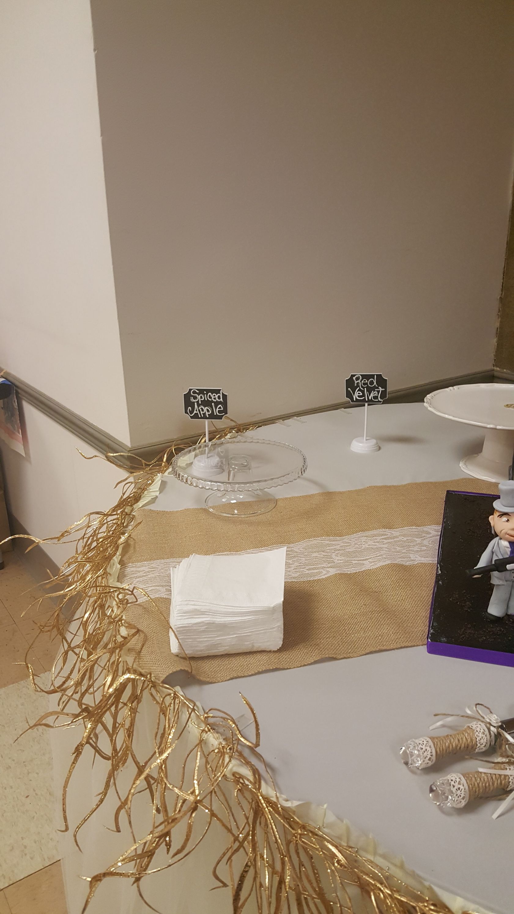 Decorated beige tabletop with white cloth, twinkling lights, and dry branches in a corner