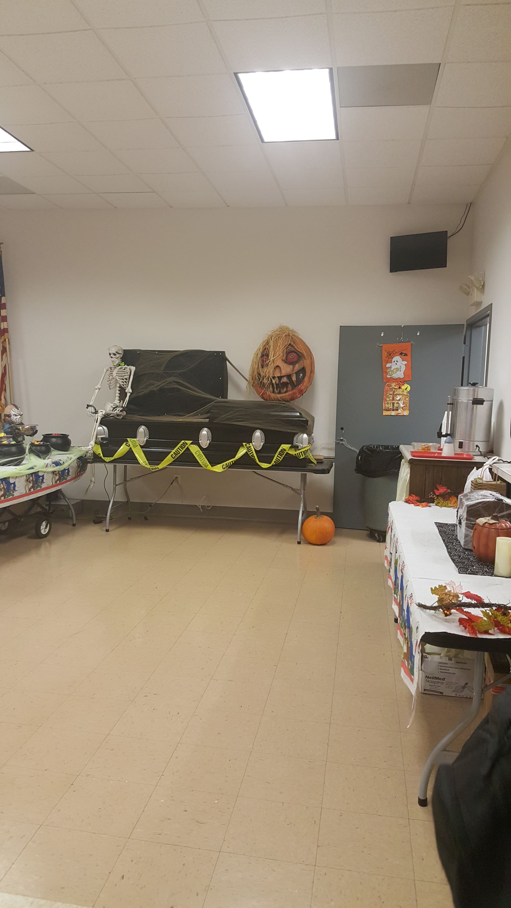 Small classroom with tables, bulletin boards, Halloween decorations, and a gray door at the back.