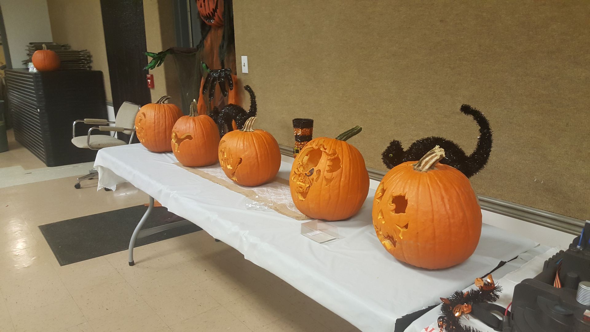 Pumpkins lined up on a long table at a Halloween display indoors