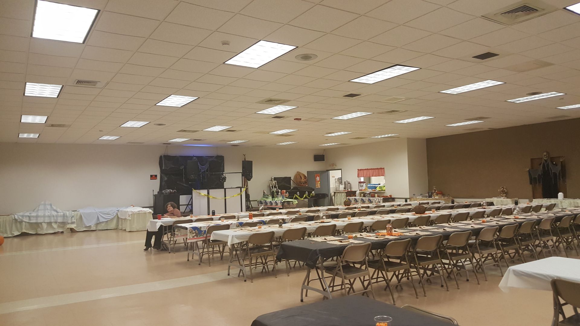 Large empty banquet hall with rows of tables and chairs under bright ceiling lights