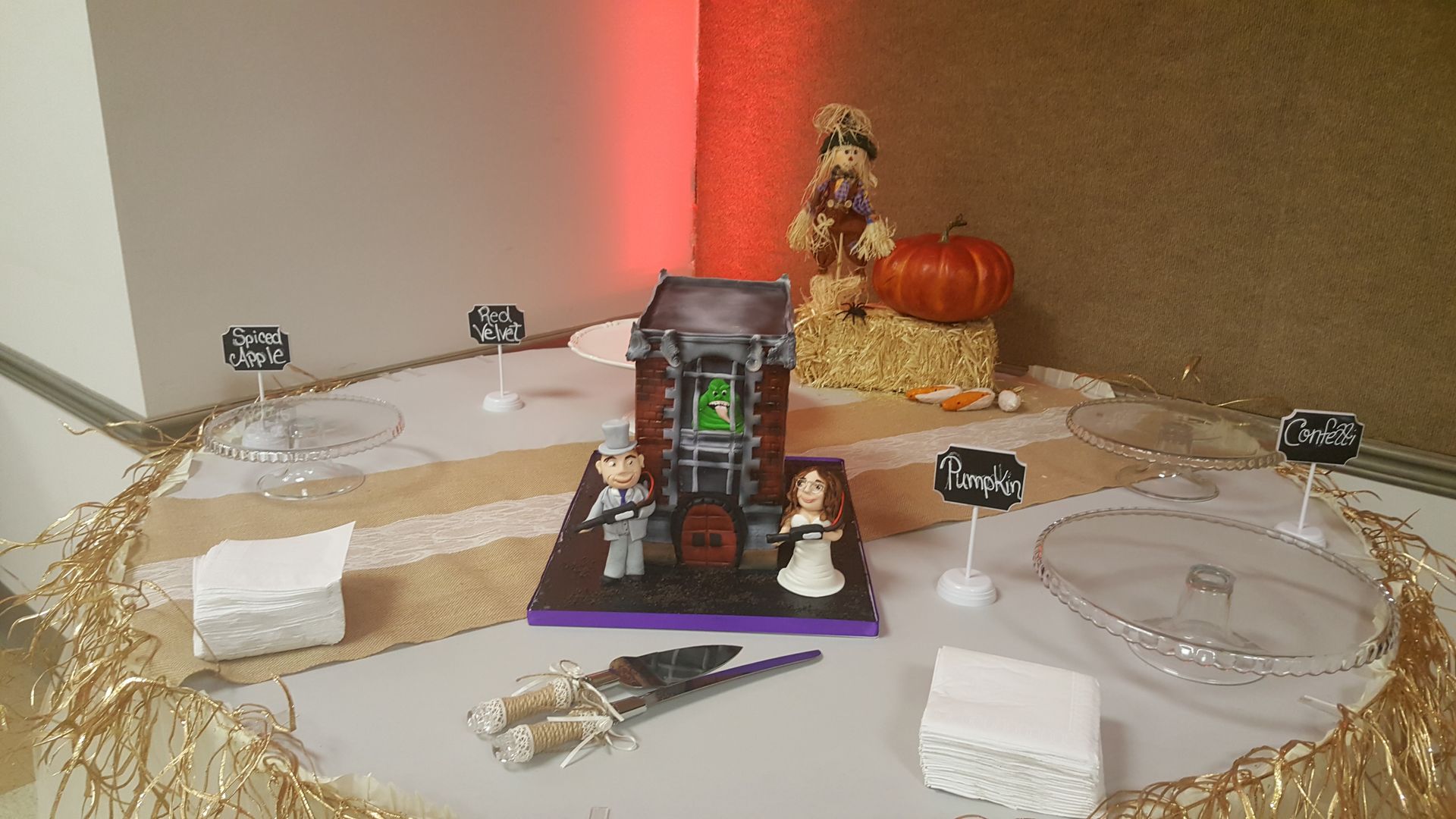 Festive altar with candles, pumpkins, flowers, and a framed centerpiece on a gold cloth.