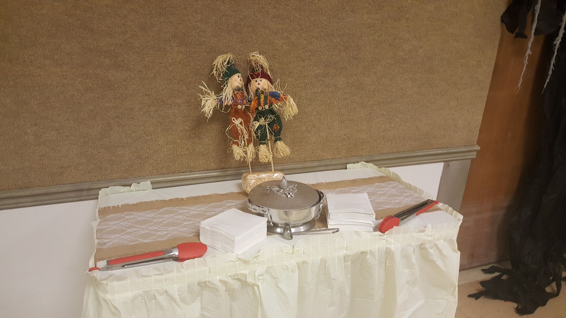 Decorated table with flowers, wrapped gifts, and a red-handled knife in a room with beige walls and a dark curtain