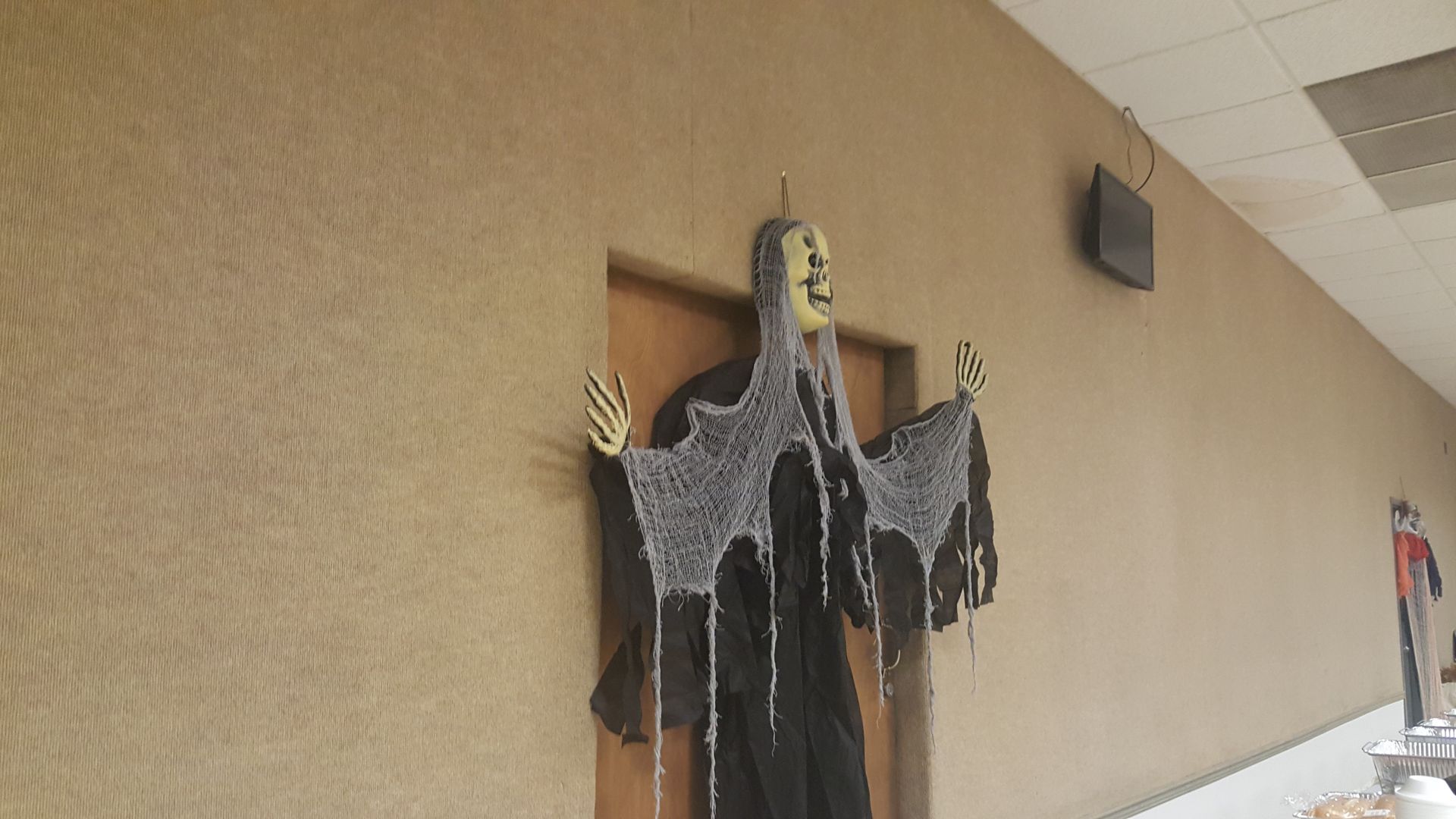 Hanging black Halloween ghost decorations on a wall in a hallway