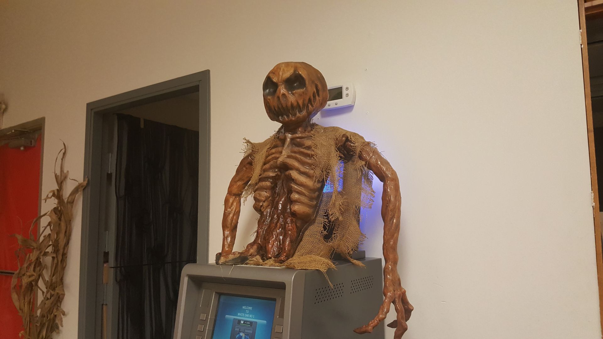 Skeleton decoration on a TV stand in a room, with dark doorway and beige walls.
