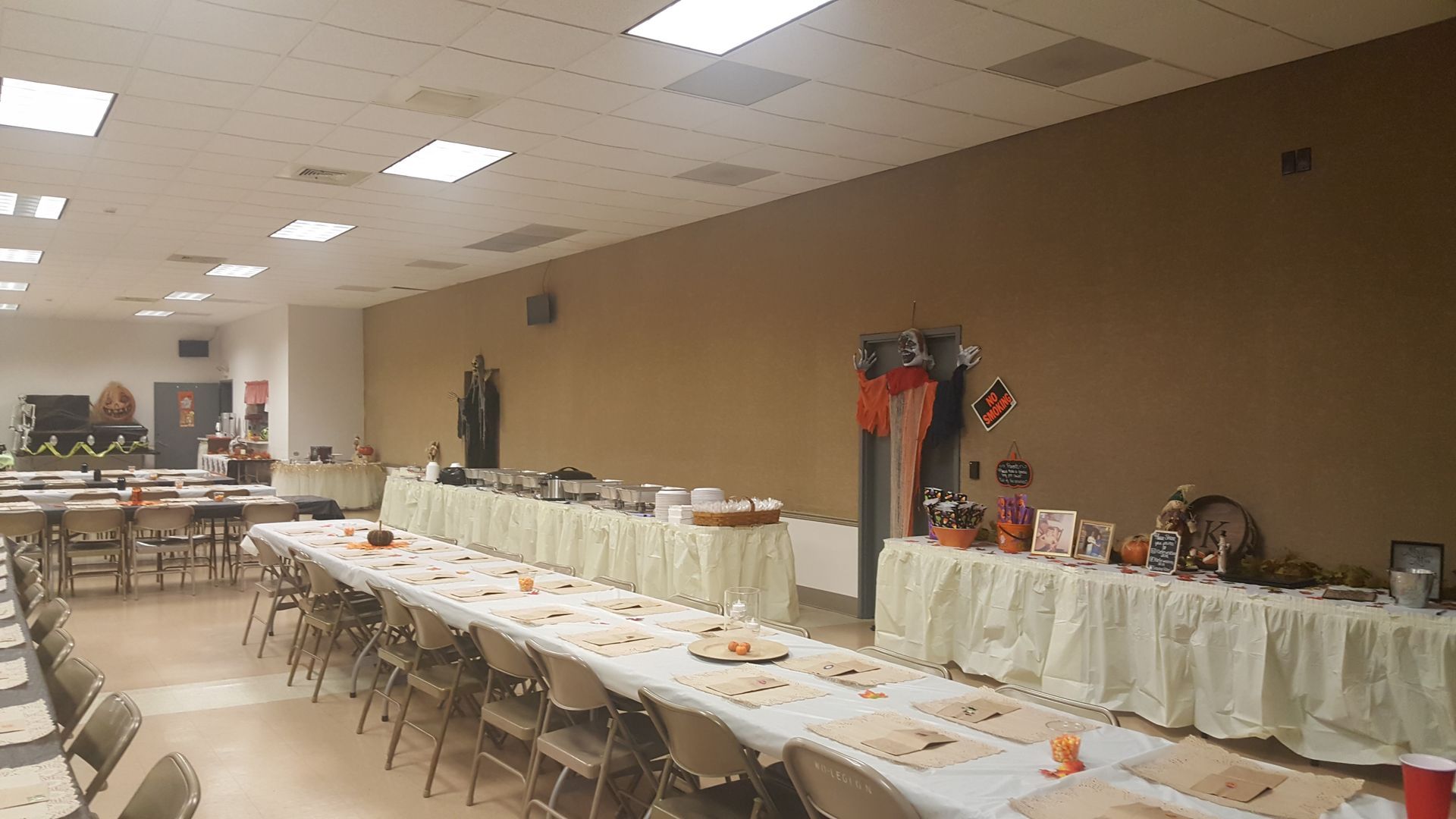 Long banquet table with white tablecloths and folded napkins in a decorated hall
