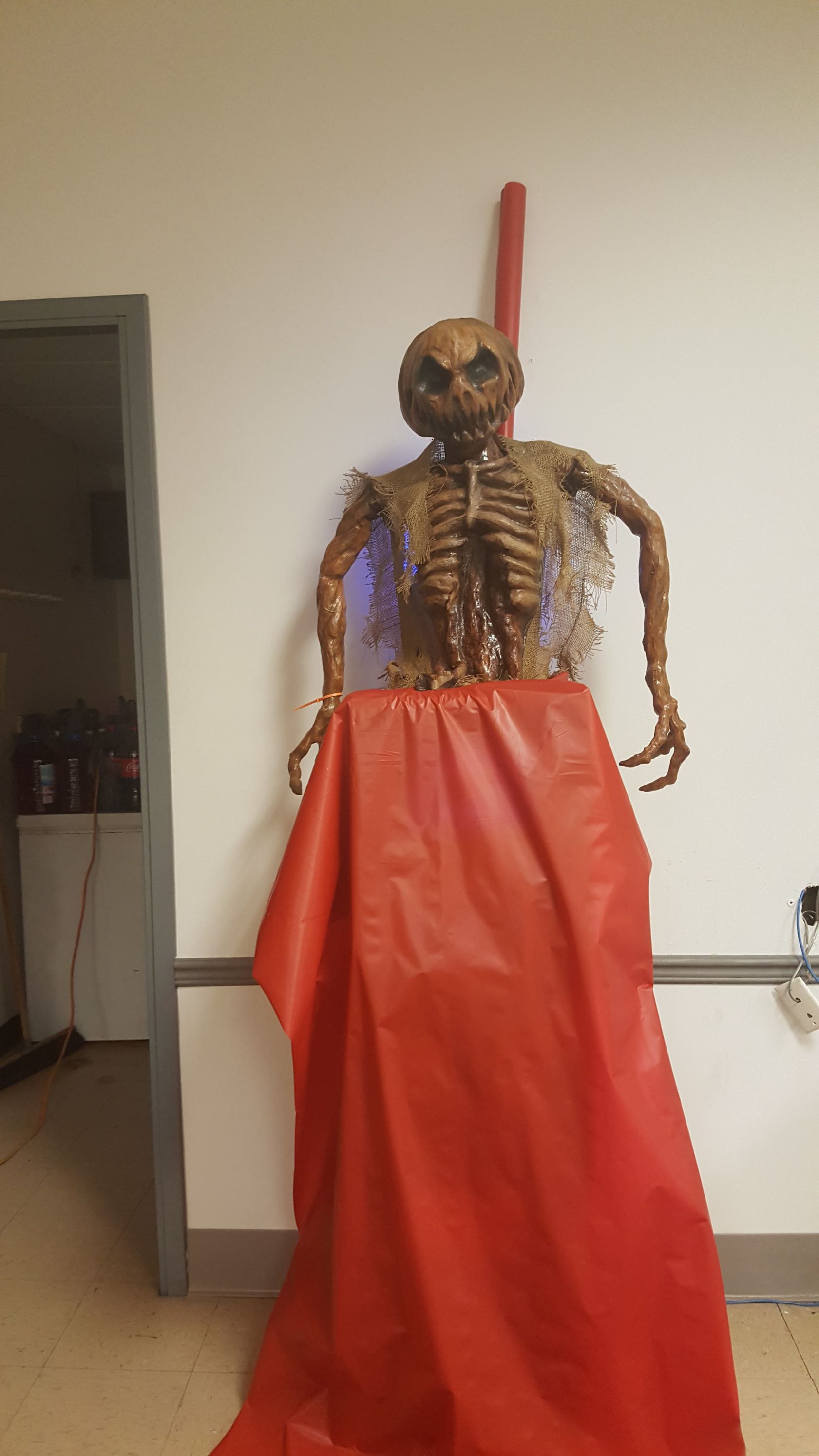 Skeleton mannequin in a red skirt displayed indoors against a wall