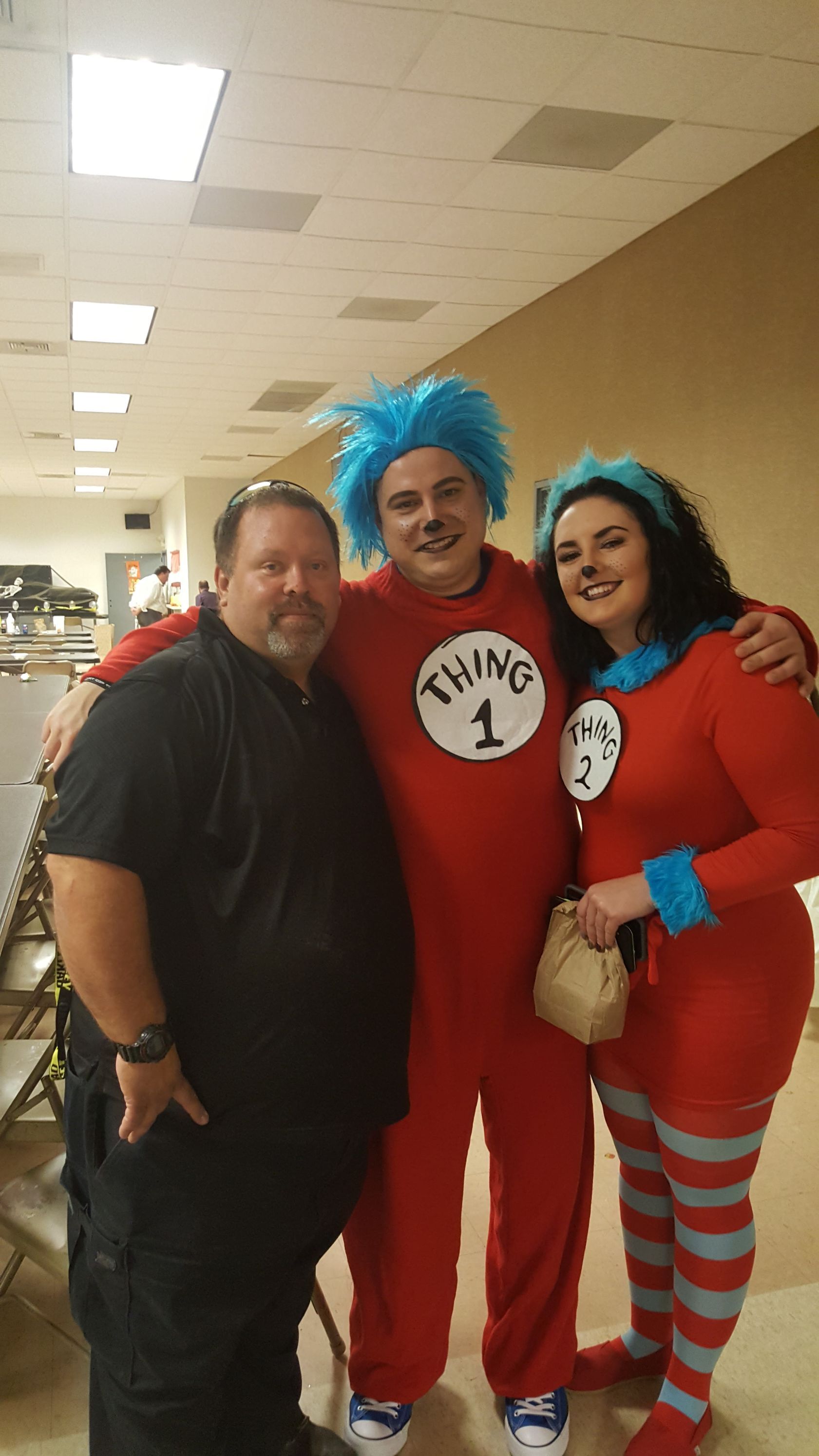 Three people in Dr. Seuss costumes posing indoors, smiling with arms around each other.