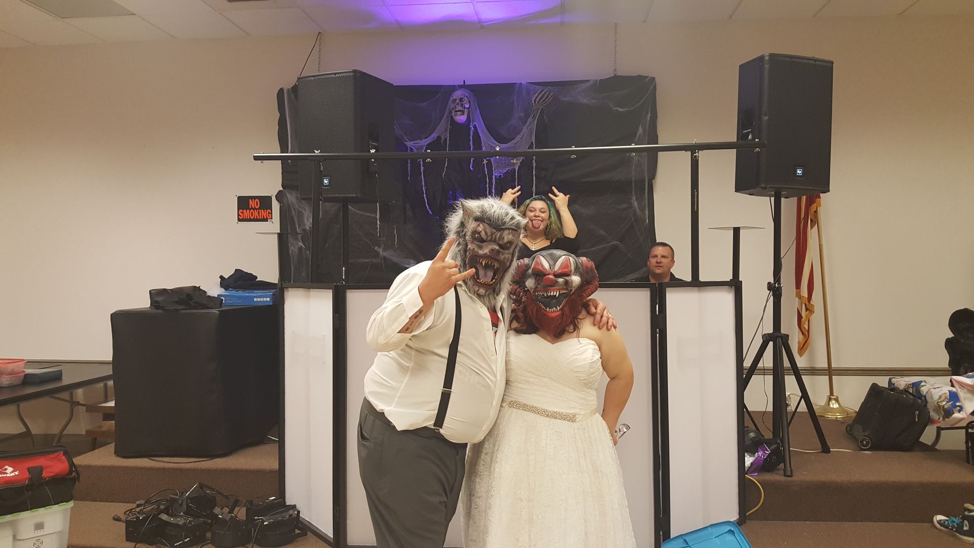 Bride and groom kissing at a wedding reception with a decorated stage and speakers behind them