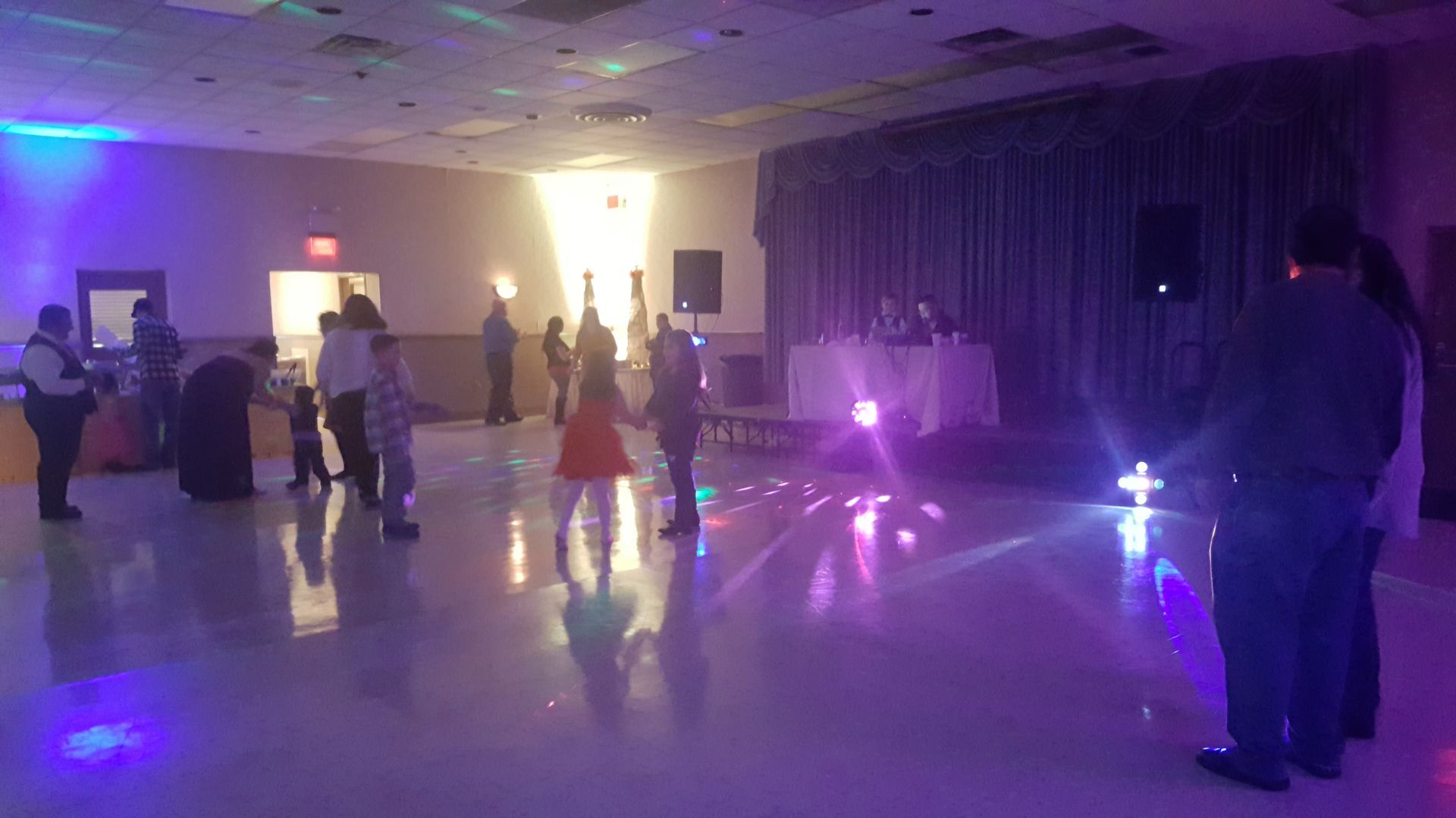 People dancing at a dimly lit party with purple stage lights in a ballroom