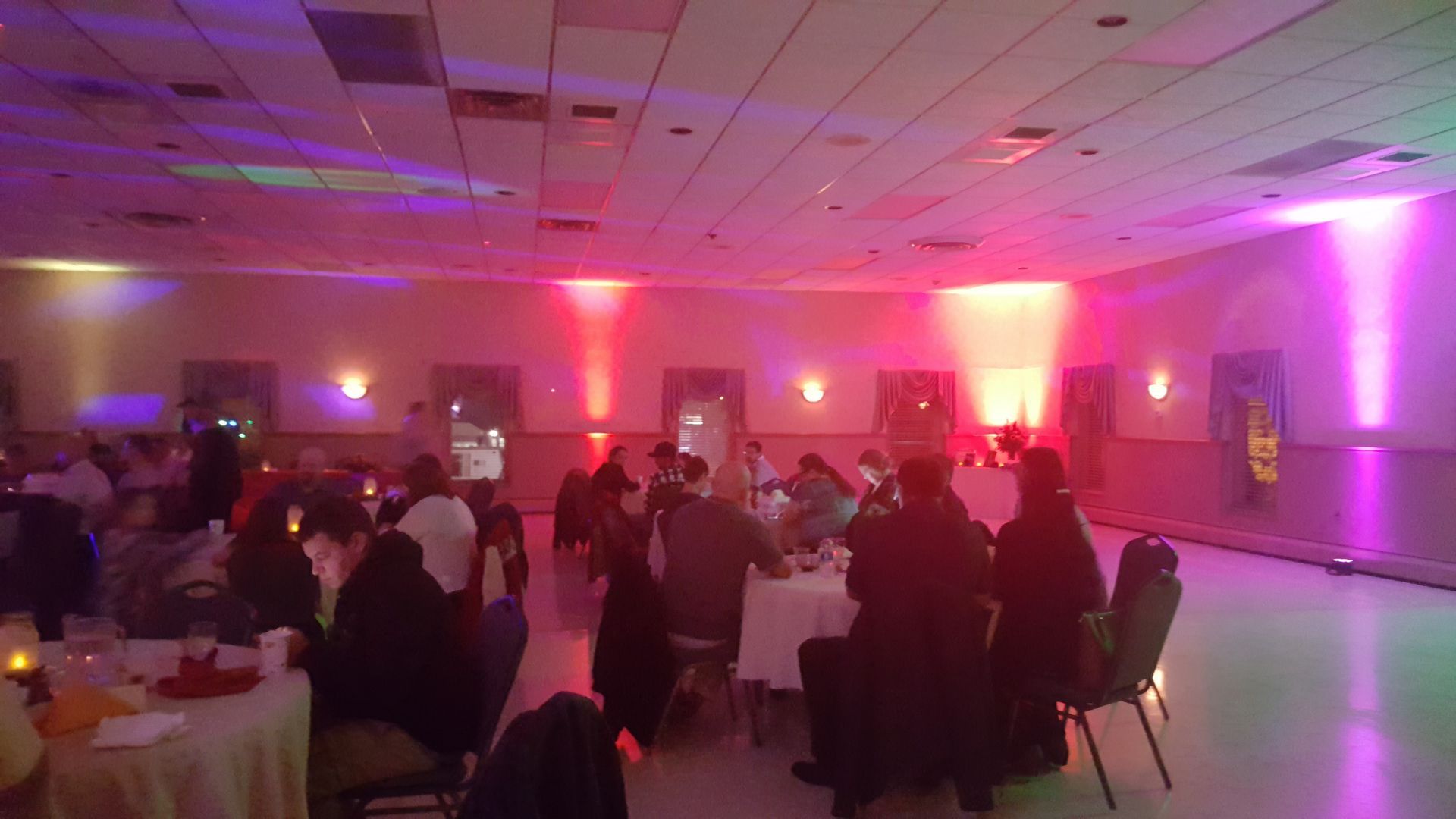 Guests seated at round tables in a pink-lit banquet hall during an event