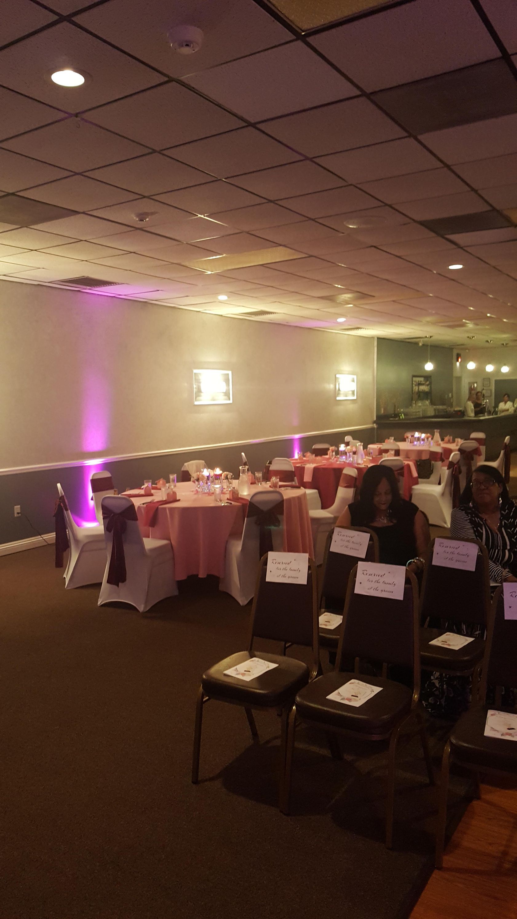 Banquet hall with pink uplighting, round tables set for dining, and chairs arranged around the room