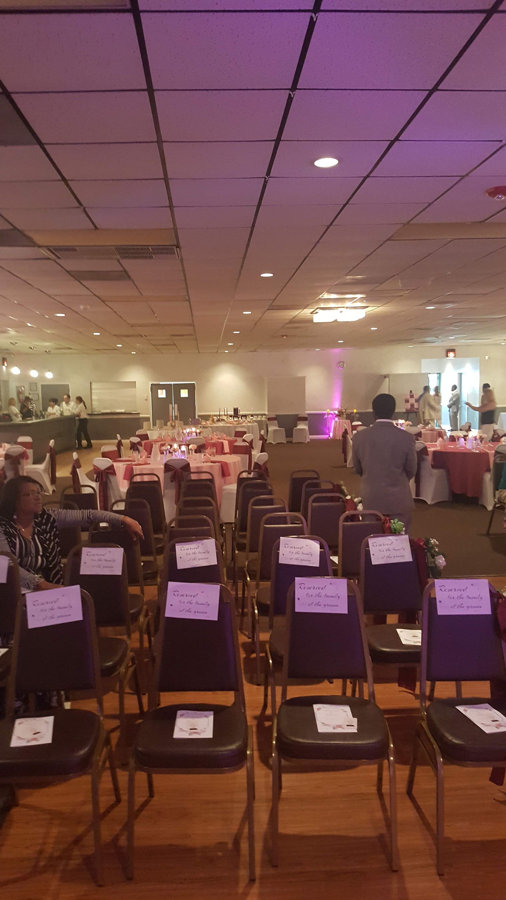 Rows of folded chairs in a banquet hall with a lit stage and purple lighting at the front