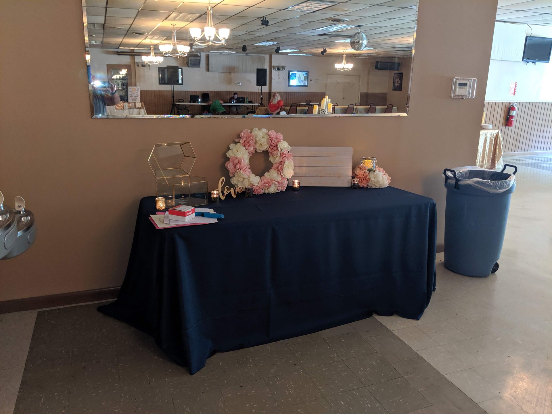 Black table with flowers and a gift basket in a bright lobby or event hall