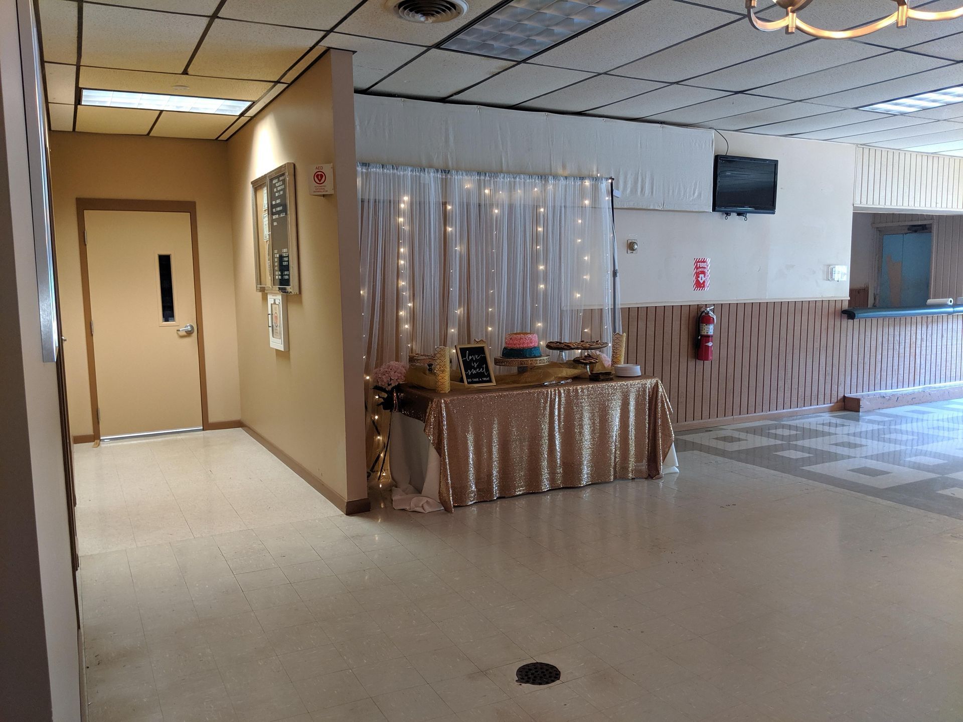 Empty hallway with beige walls, tiled floor, and a draped table near a reception counter