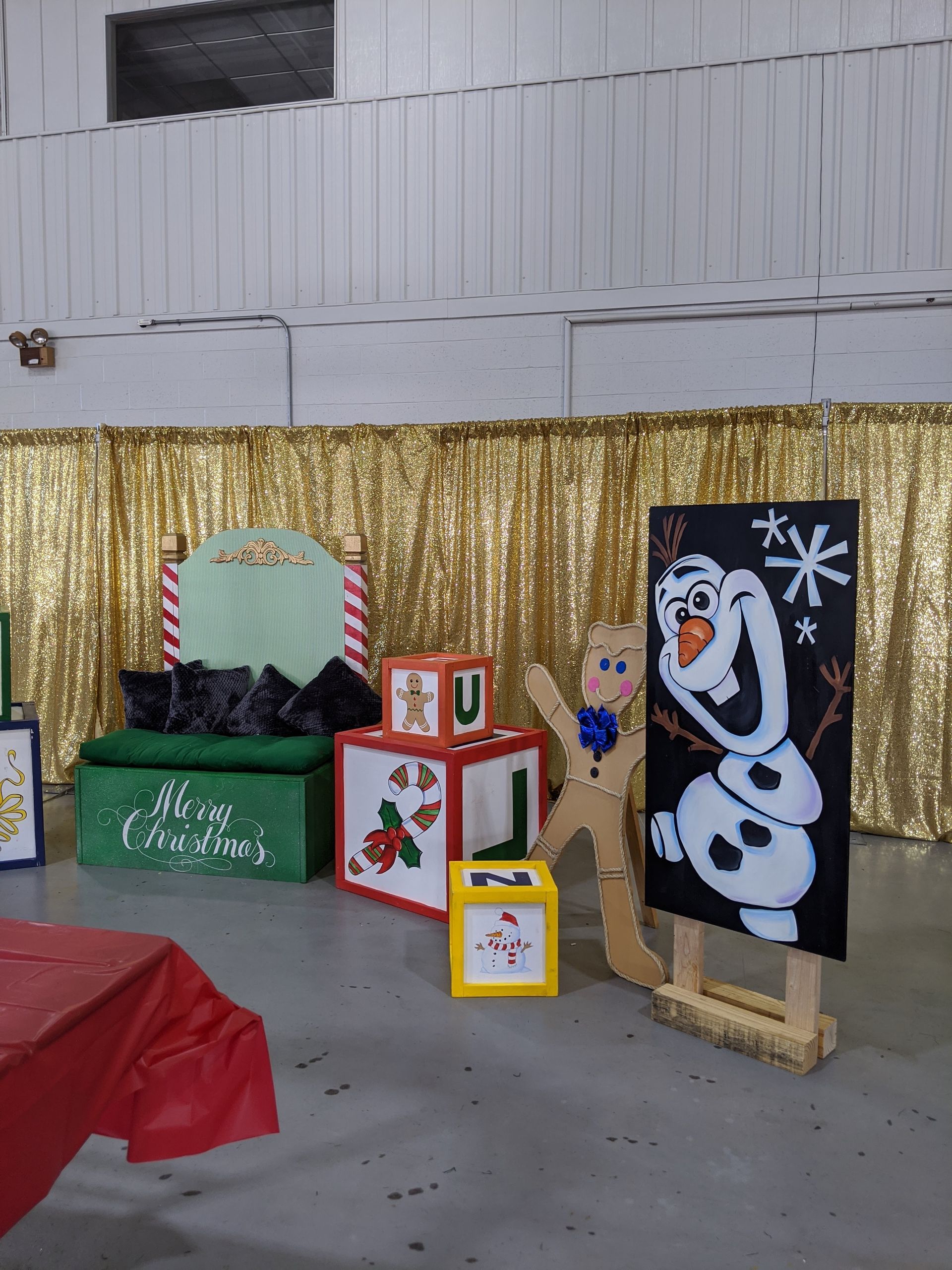 Holiday display with Olaf cutout, gold tinsel backdrop, wrapped boxes, and a green Christmas mailbox display