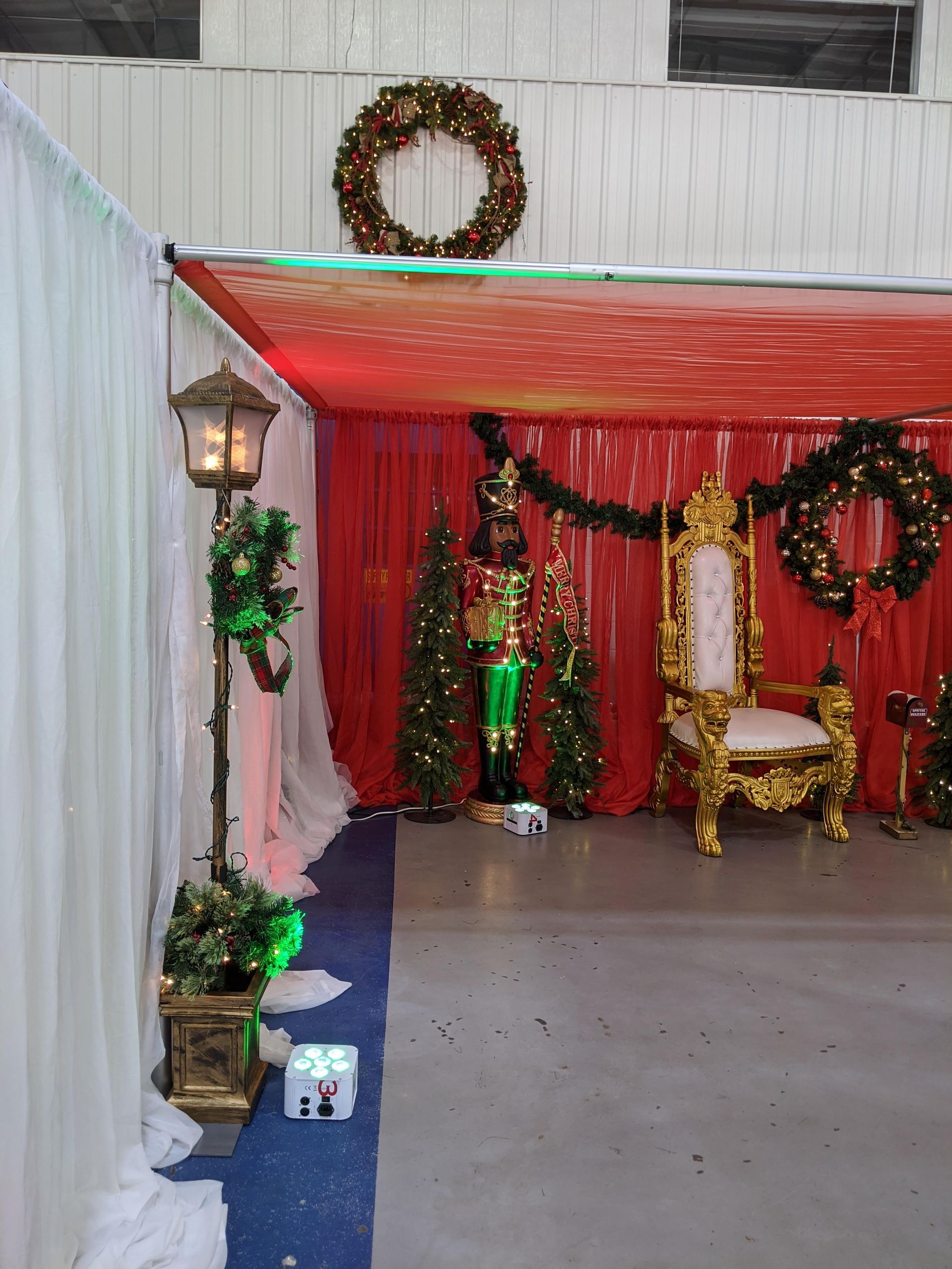 Festive red-and-gold outdoor patio with wreaths, garlands, and decorative chairs under a canopy