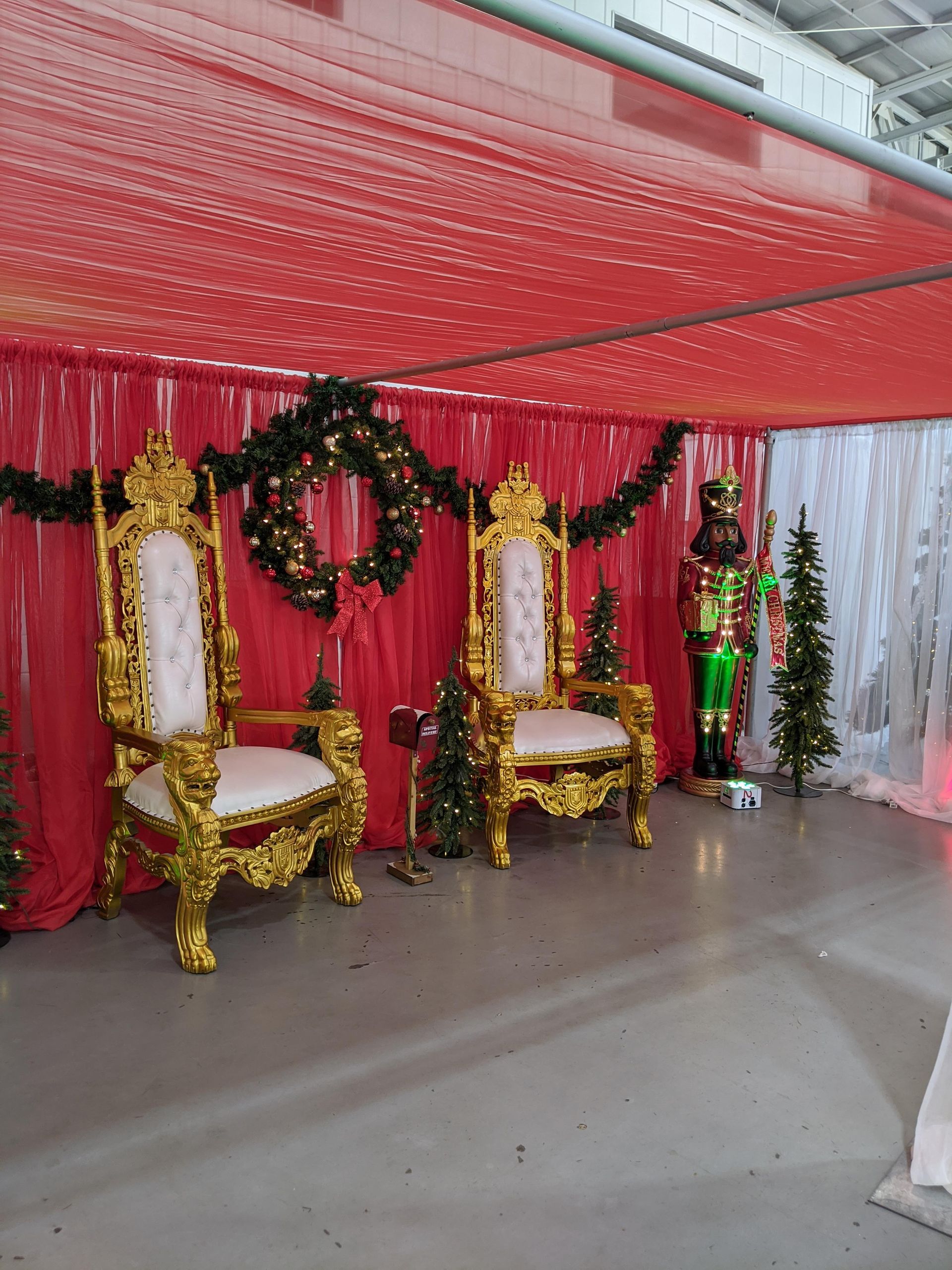 Decorated red-and-gold banquet stage with chairs, wreaths, and festive drapery under a canopy