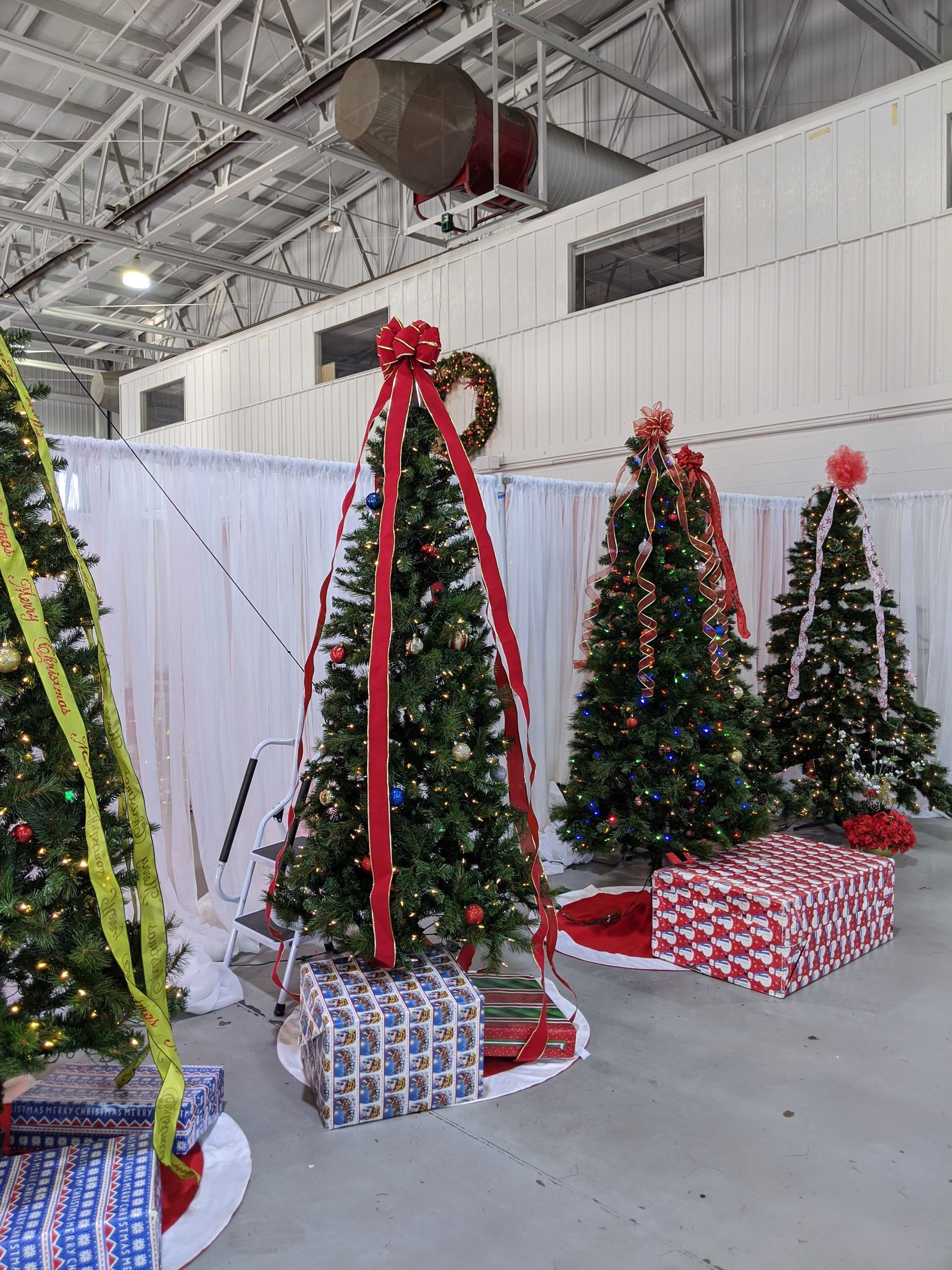 Decorated Christmas trees and wrapped gifts displayed in a bright indoor hall