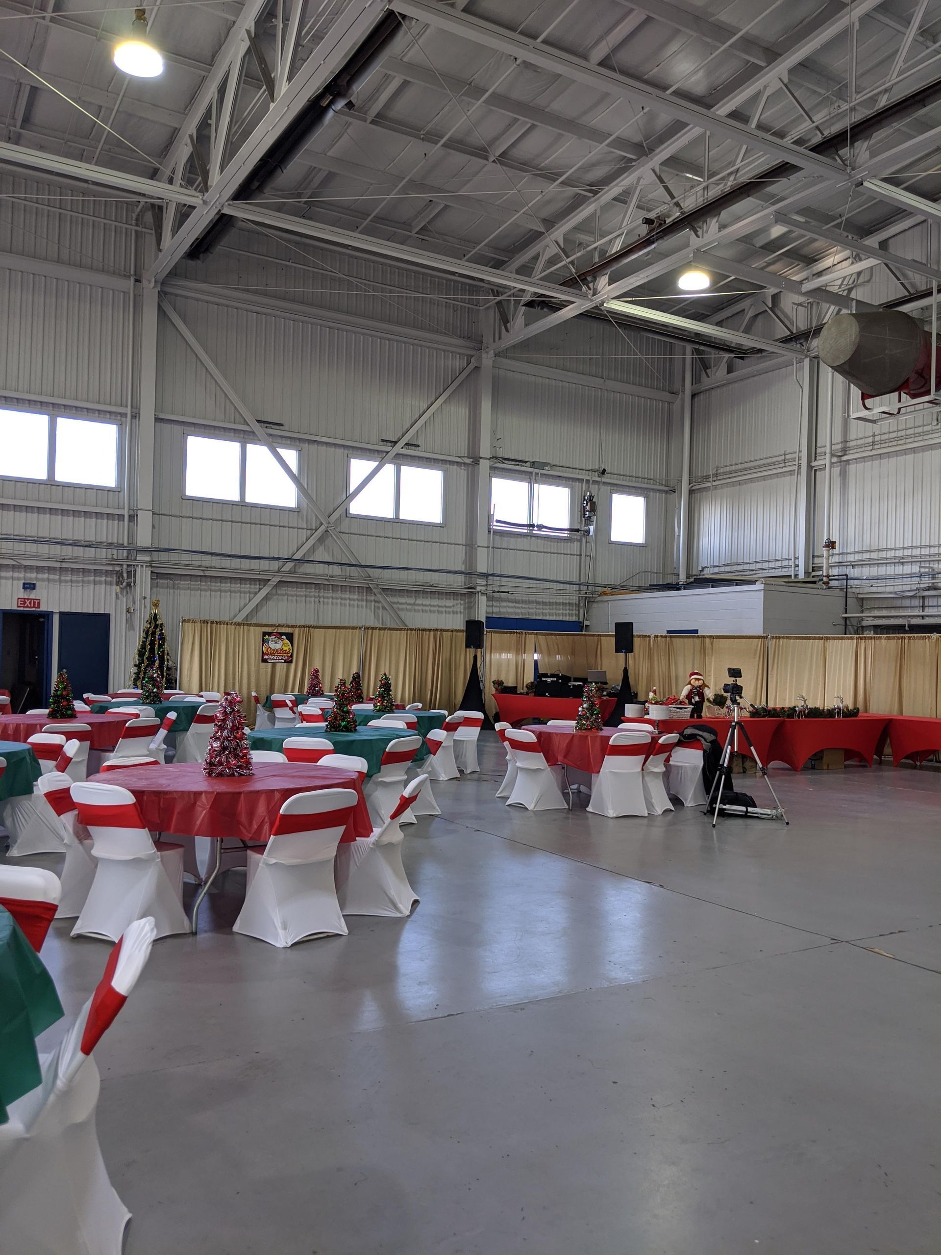 Decorated banquet hall with red-and-white table settings in a large industrial-style room