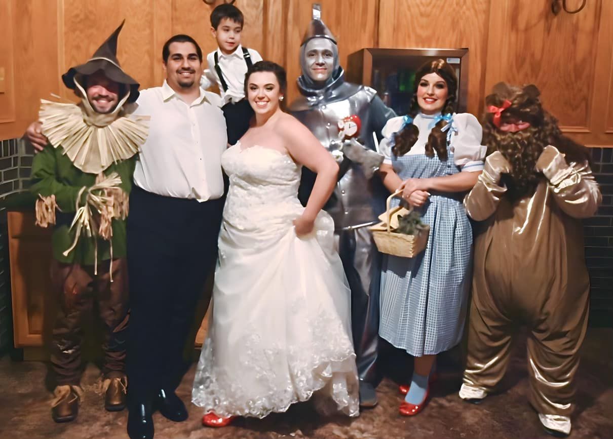 Wedding party dressed as Wizard of Oz characters, bride and groom center.