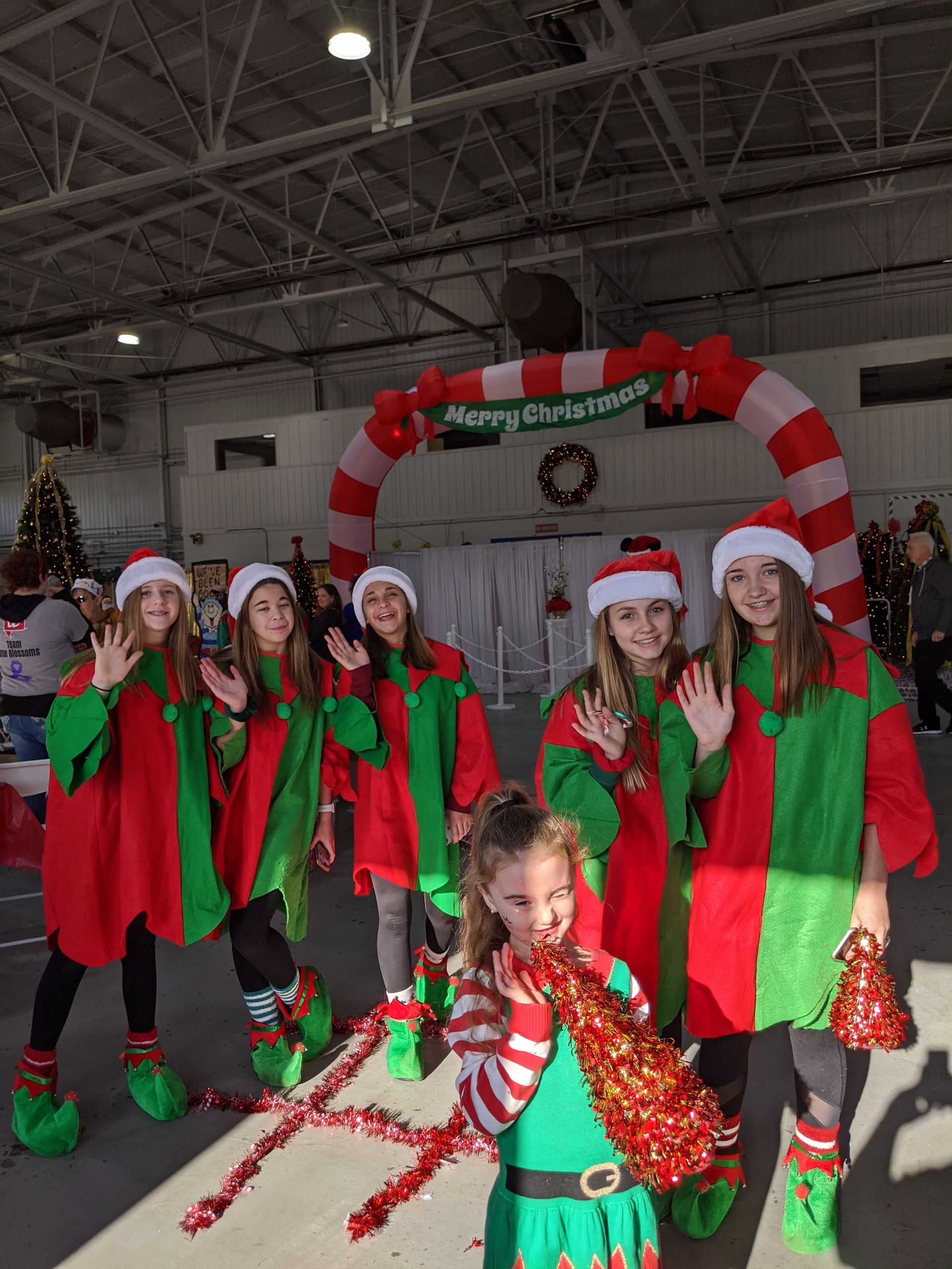 Group of people in red-and-green holiday outfits posing at a Christmas event indoors