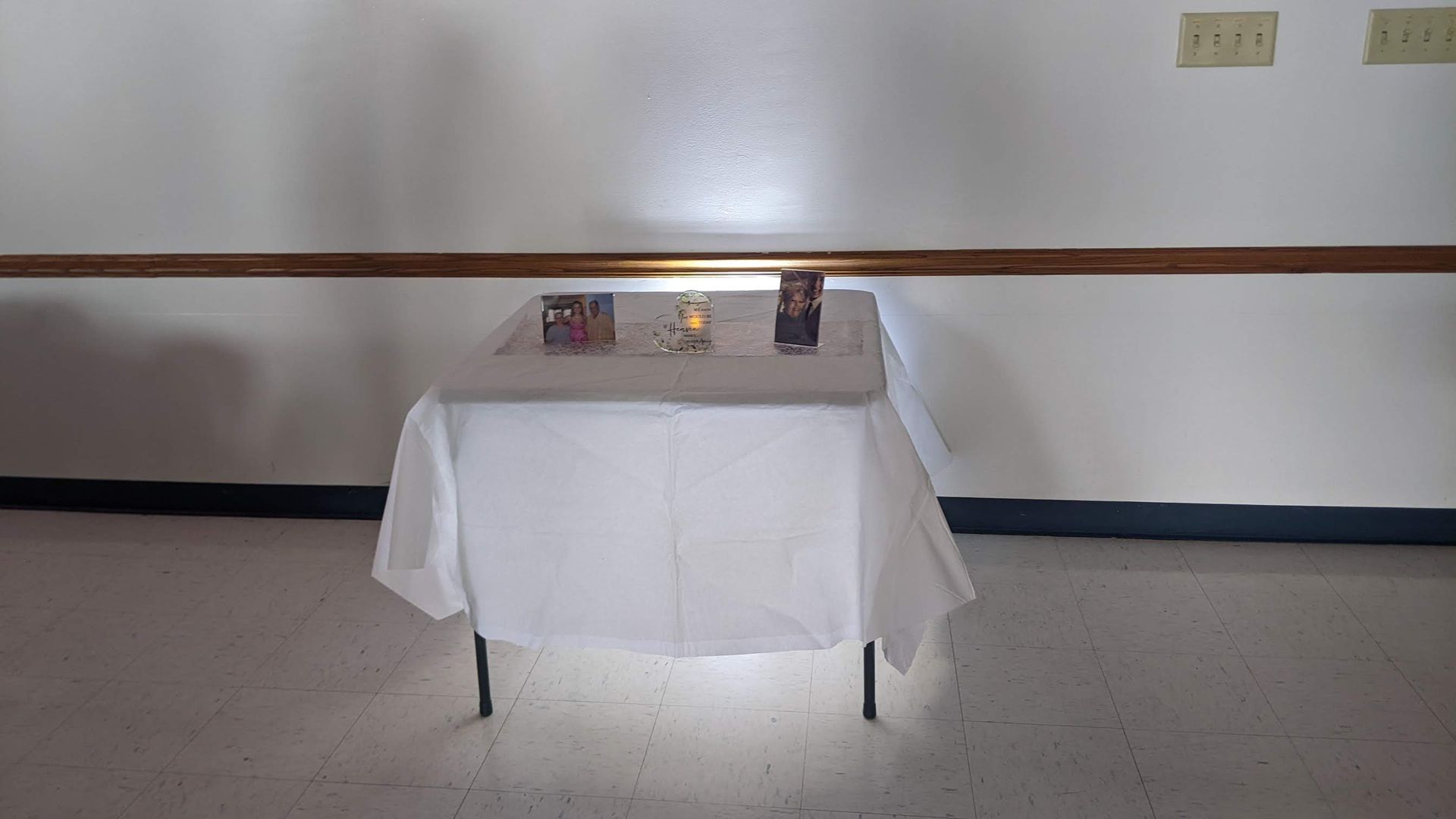 Small table with a white tablecloth against a plain wall, displaying a few small items.