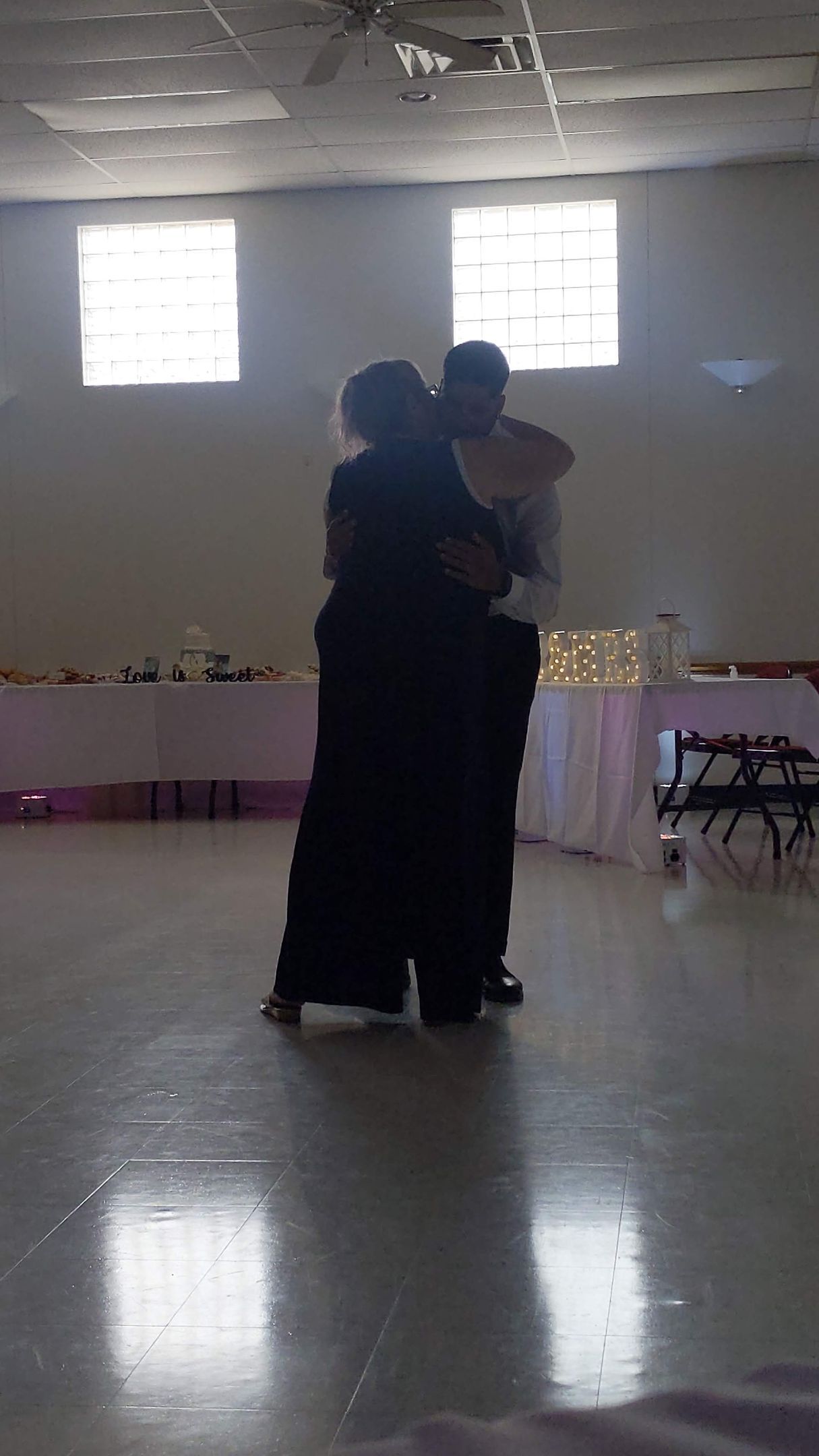 Two people slow dancing in a bright banquet hall during a reception