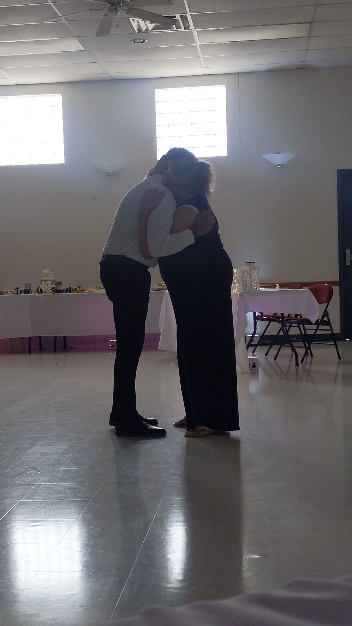 Two people hugging in a bright empty room with a shiny floor