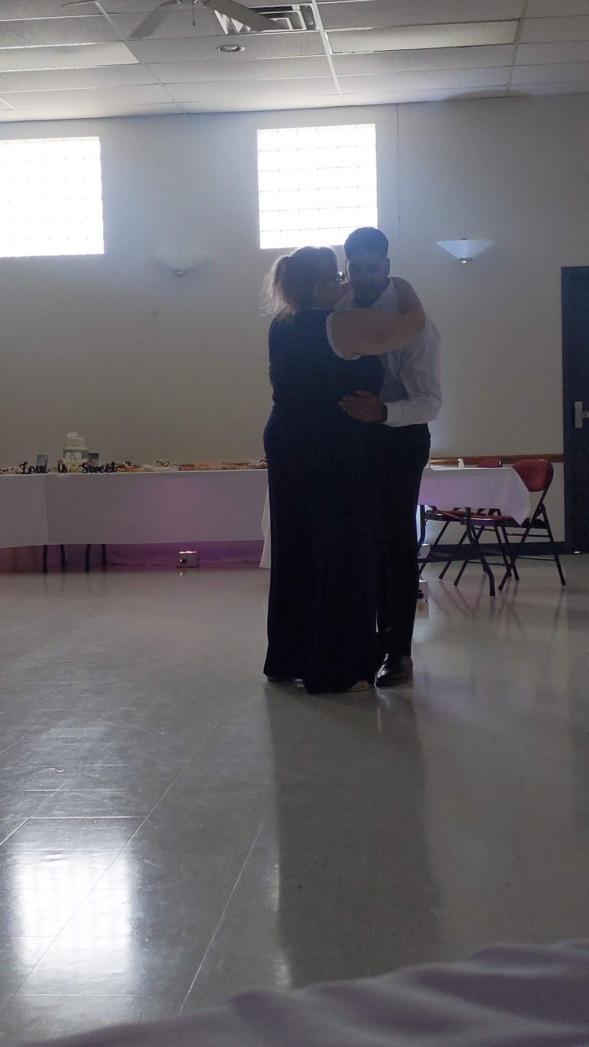 Two people embracing on a polished dance floor in a bright hall