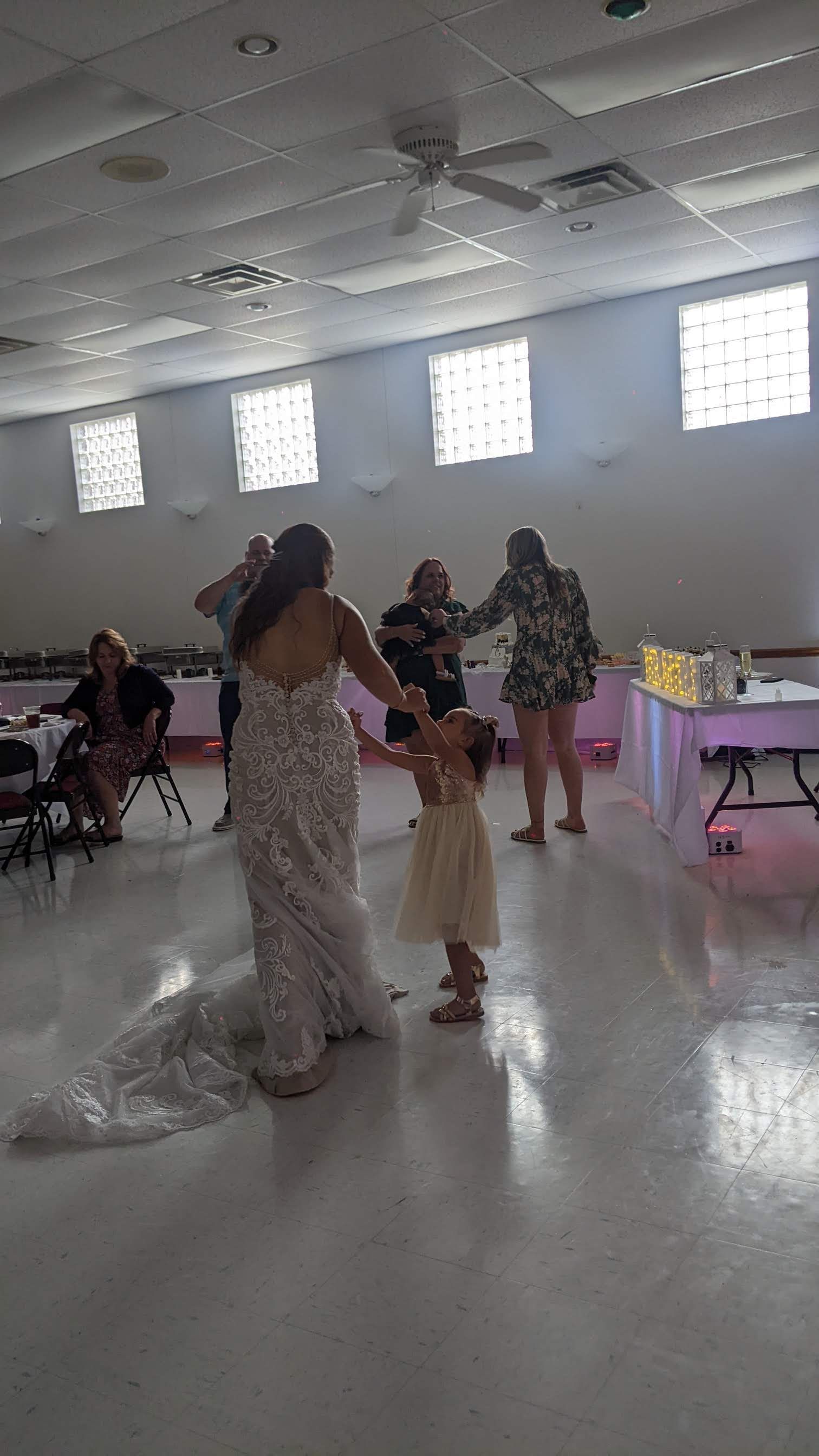 Bride and guests dancing at a wedding reception in a bright hall