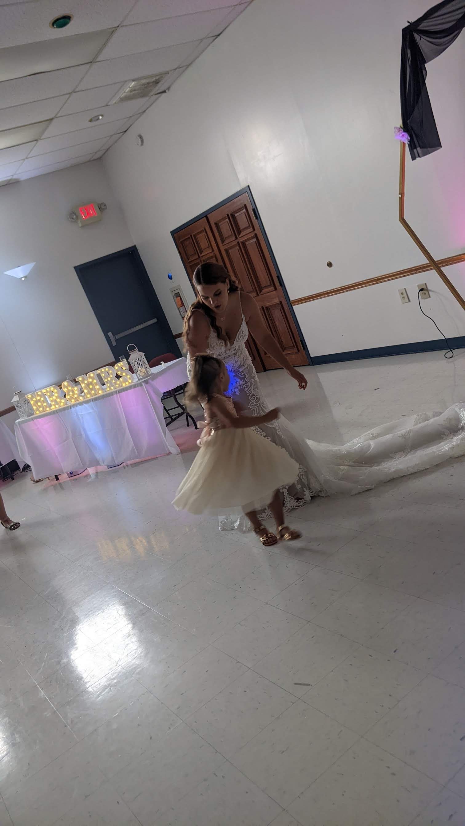 Bride in a white gown posing in a decorated banquet hall during a celebration.