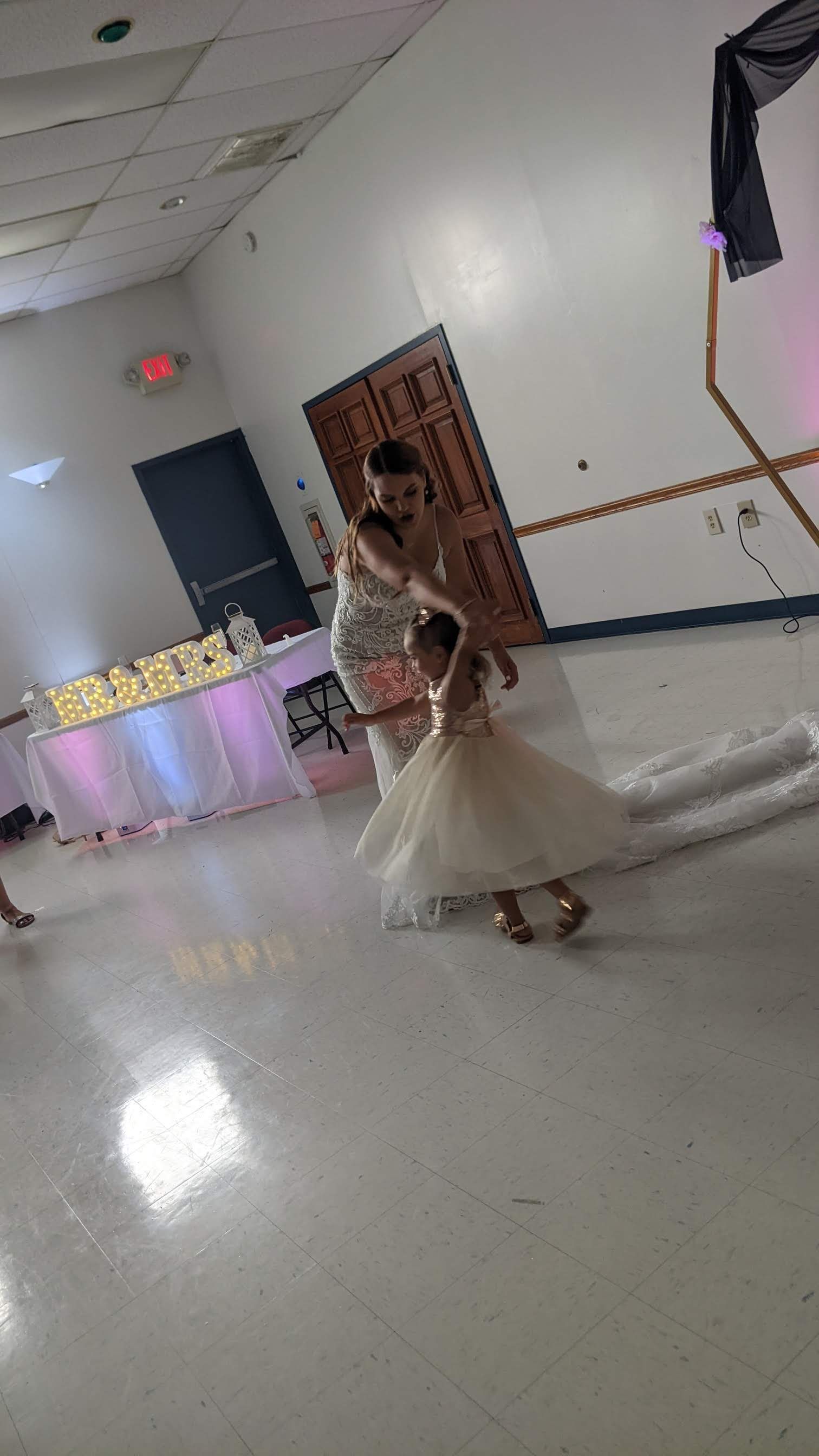 Person in a white gown dancing in a decorated banquet hall.