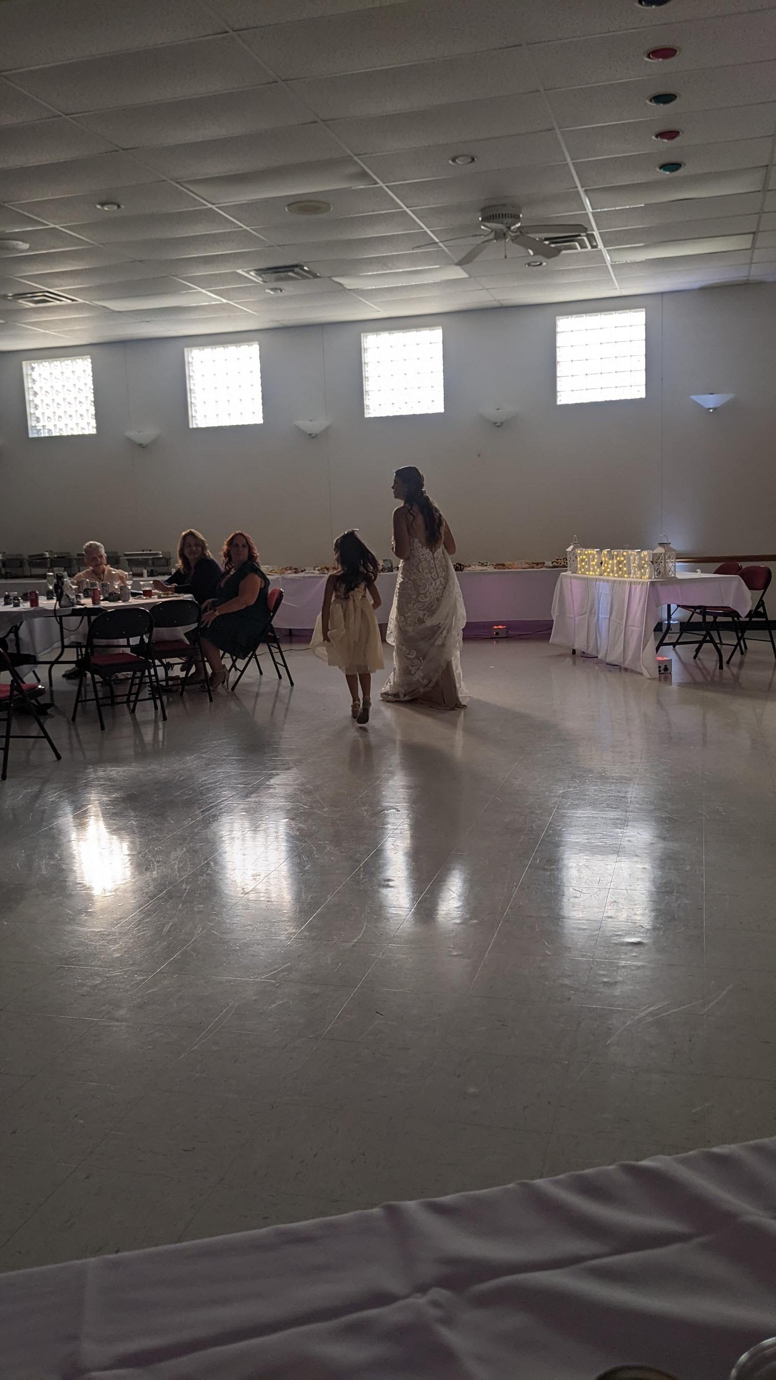 Banquet hall with guests seated at tables while a woman stands near the center floor.